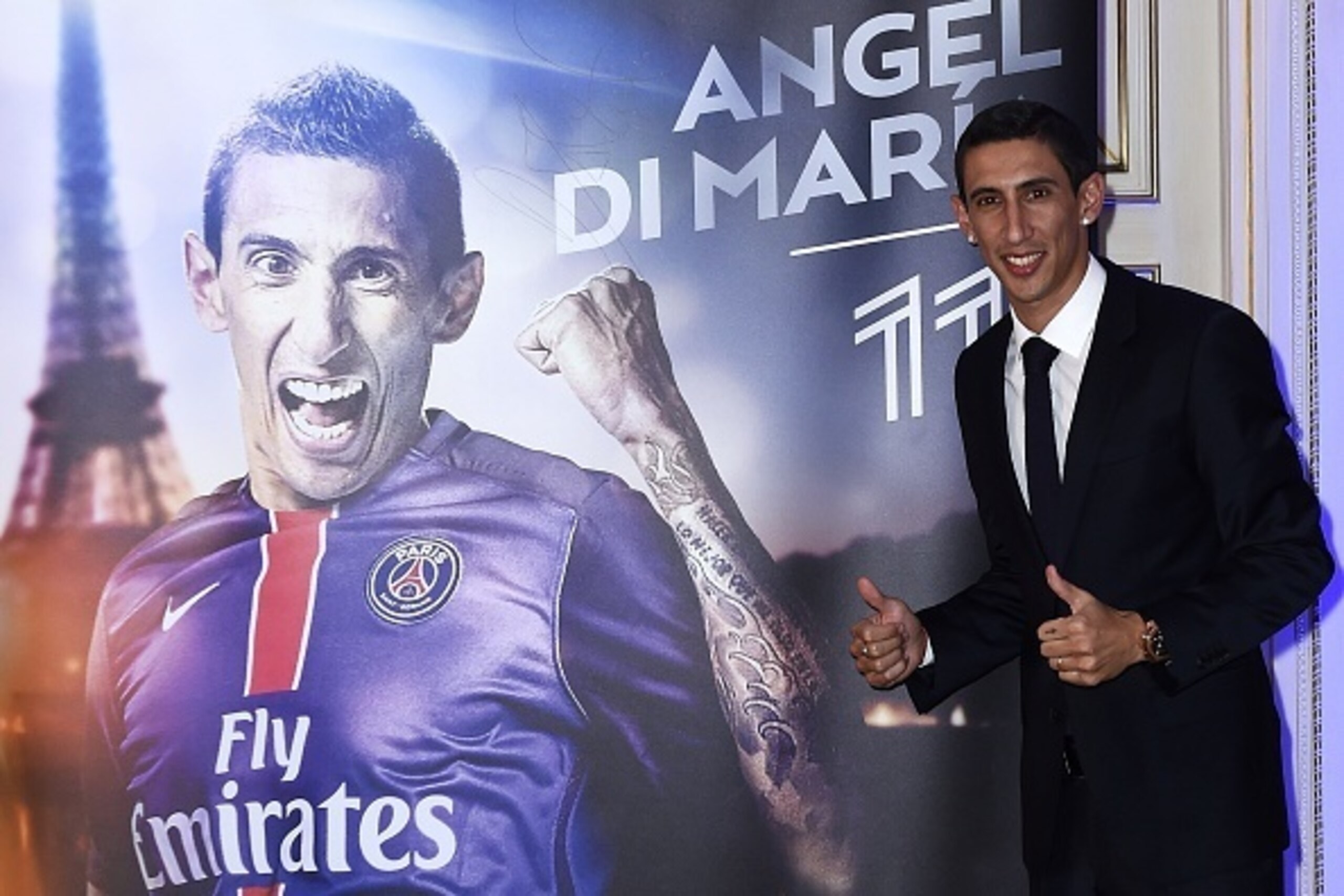 Paris Saint-Germain's (PSG) new Argentinian midfielder Angel Di Maria gives two thumbs up as he poses next to a poster during his official presentation in Paris on August 6, 2015. Paris Saint-Germain completed the signing of Di Maria from Manchester Unite