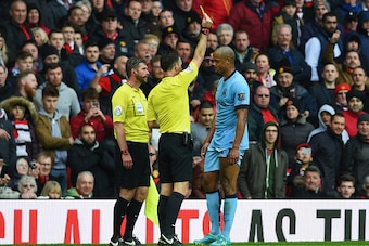 MANCHESTER, ENGLAND - APRIL 12:  Vincent Kompany of Manchester City is shown a yellow card by referee Mark Clattenburg during the Barclays Premier League match between Manchester United and Manchester City at Old Trafford on April 12, 2015 in Manchester, 