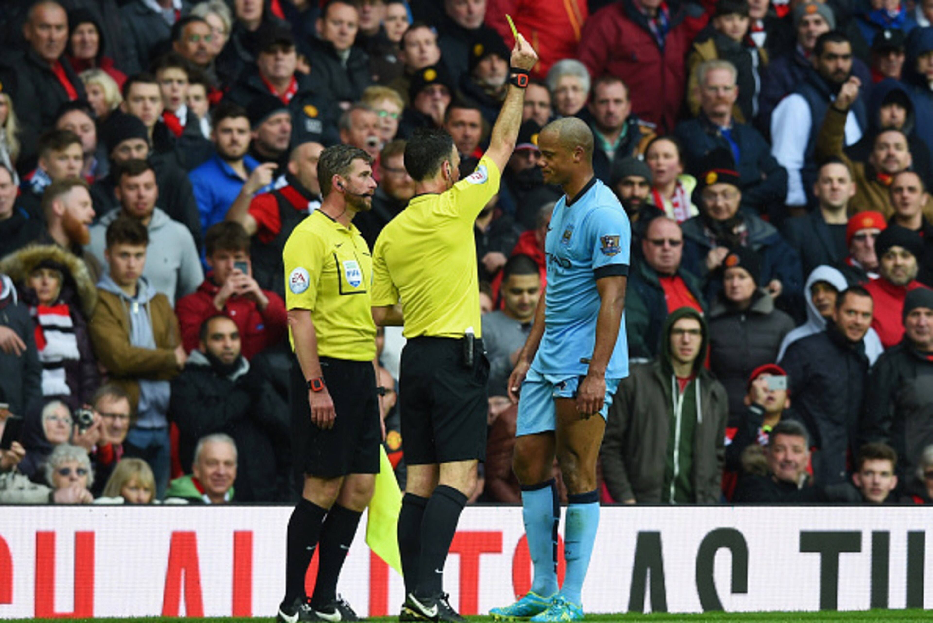 MANCHESTER, ENGLAND - APRIL 12:  Vincent Kompany of Manchester City is shown a yellow card by referee Mark Clattenburg during the Barclays Premier League match between Manchester United and Manchester City at Old Trafford on April 12, 2015 in Manchester, 