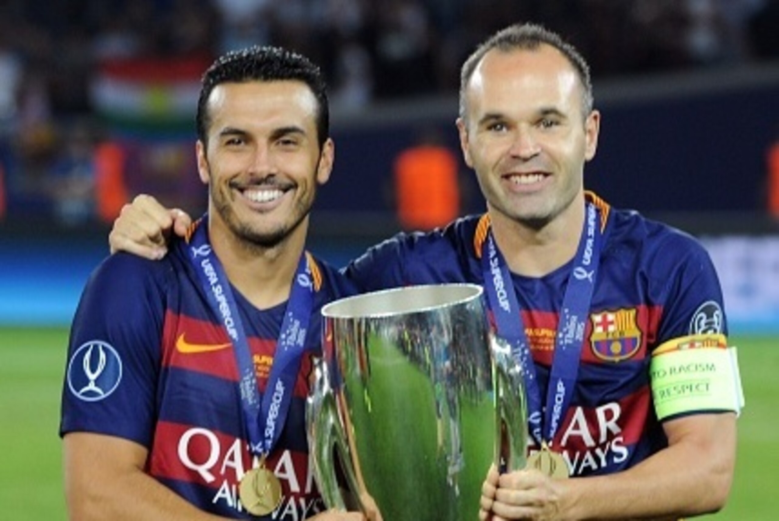 Barcelona's midfielder Andres Iniesta (L) and Barcelona's forward Pedro Rodriguez celebrate with the trophy after winning the UEFA Super Cup final football match between FC Barcelona and Sevilla FC on August 11, 2015 at the Boris Paichadze Dinamo Arena in