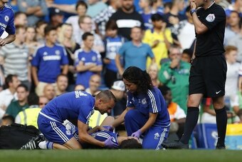Chelsea doctor Eva Carneiro (R) and head physio Jon Fearn (L) treat Chelsea's Belgian midfielder Eden Hazard late on next to referee Michael Oliver (R) during the English Premier League football match between Chelsea and Swansea City  at Stamford Bridge i