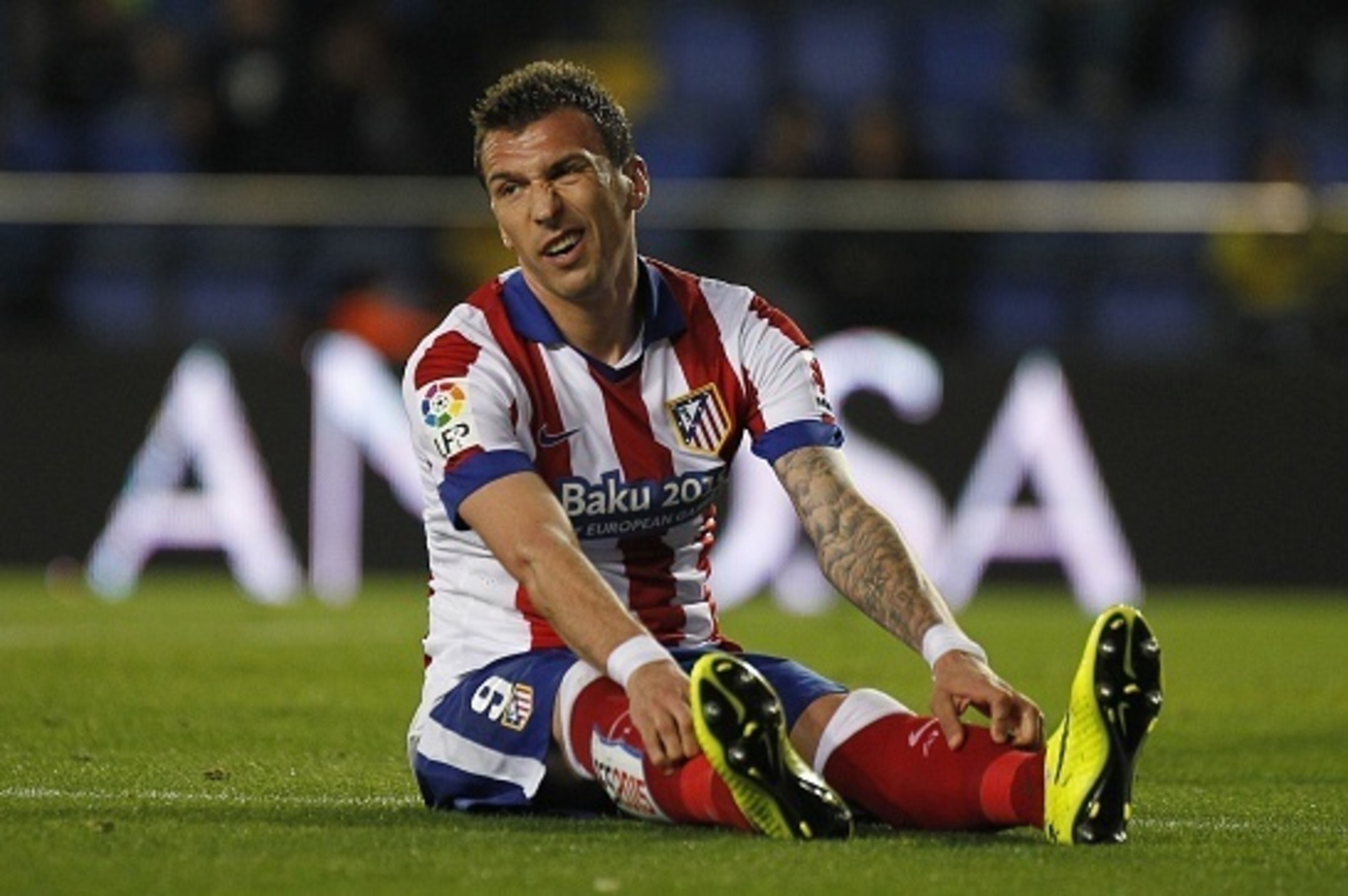 Atletico Madrid's Croatian forward Mario Mandzukic sits on the pitch grimacing during the Spanish league football match Villarreal CF vs Club Atletico de Madrid at El Madrigal stadium in Villareal on April 29, 2015.   AFP PHOTO/ JOSE JORDAN        (Photo 