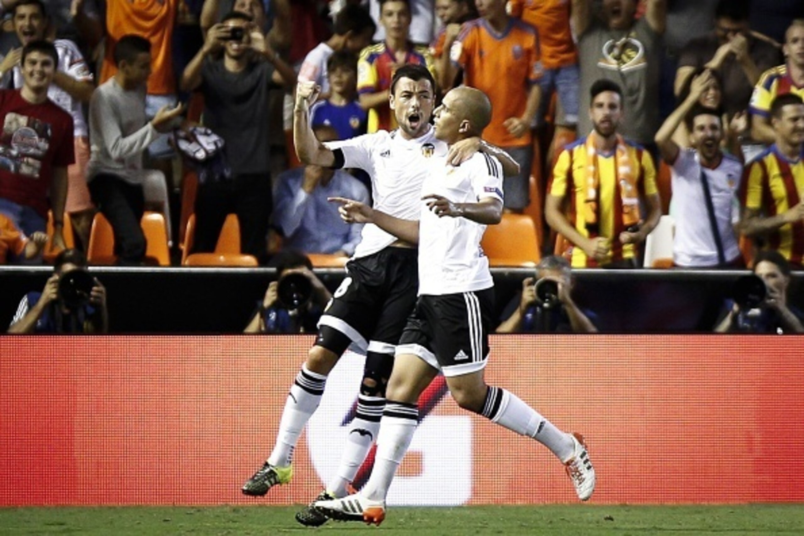 Valencia's French midfielder Sofiane Feghouli (R) celebrates with a teammate after scoring during the UEFA Champions League playoff football match between Valencia CF vs AS Monaco FC at the Mestalla stadium in Valencia on August 19, 2014.  AFP PHOTO/ BIEL