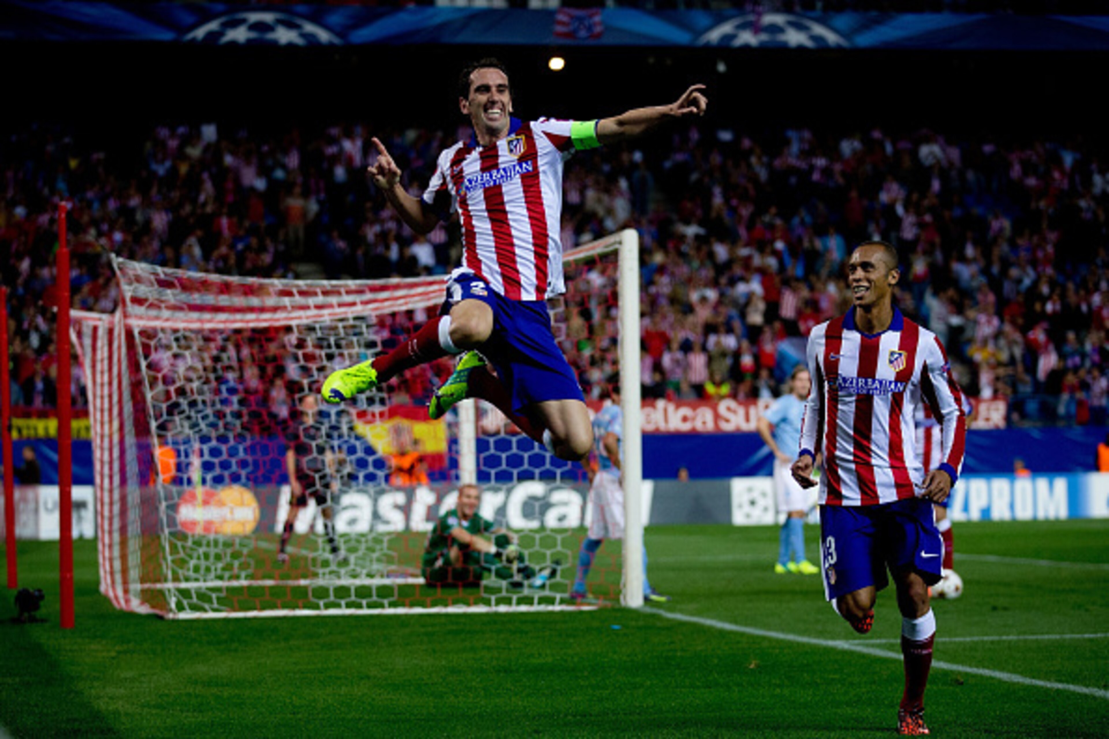 MADRID, SPAIN - OCTOBER 22: Diego Godin (L) jumps to celebrate scoring their fourth goal close to his team mate Joao Miranda (R) during the UEFA Champions League group A match between Club Atletico de Madrid and Malmo FF at Vicente Calderon stadium on Oct