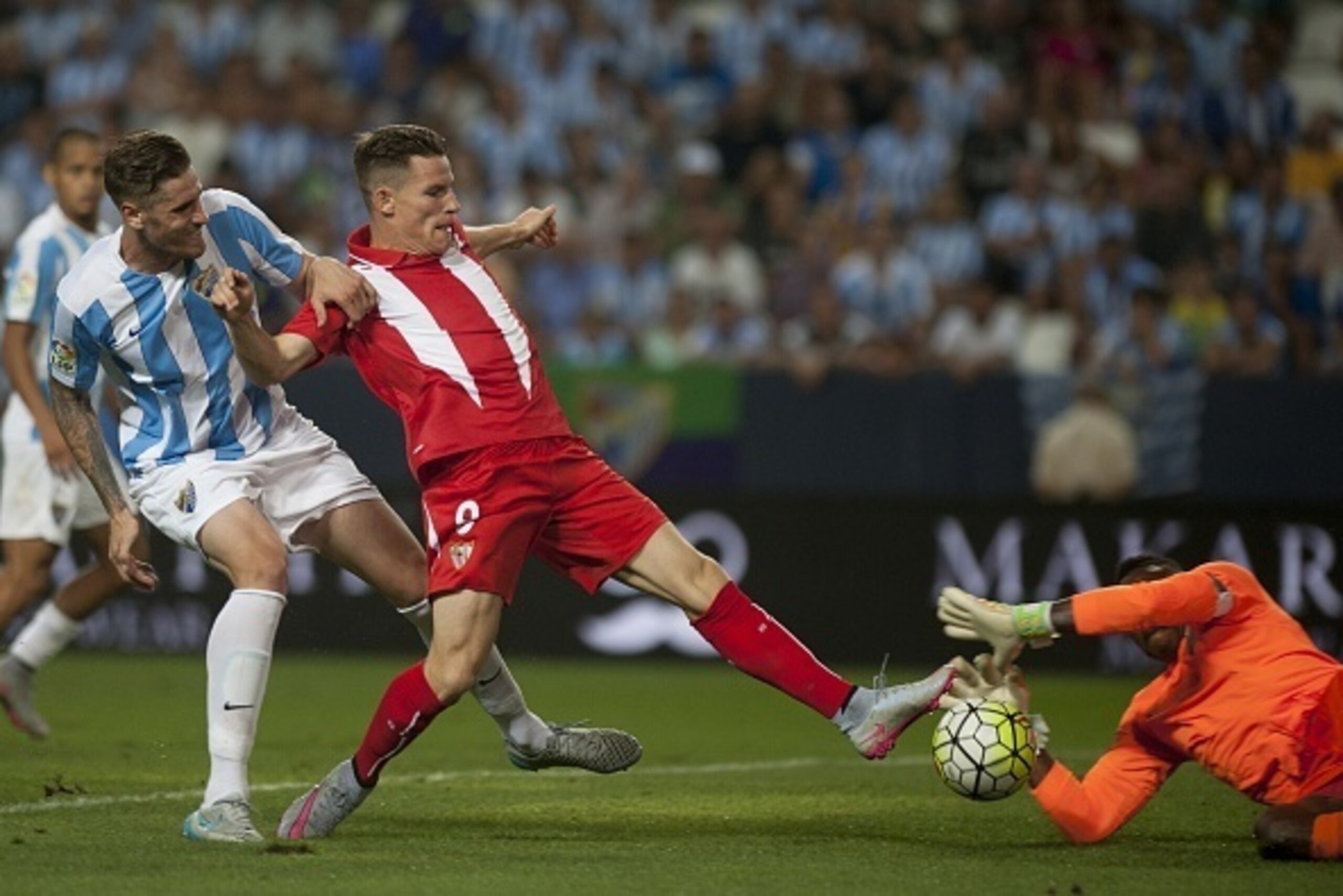 Malaga's defender Raul Albentosa (L) and Malaga's Cameroonian goalkeeper Carlos Kameni (R) vies with Sevilla's French forward Kevin Gameiro during the Spanish league football match Malaga CF vs Sevilla FC at La Rosaleda stadium in Malaga on August 21, 201