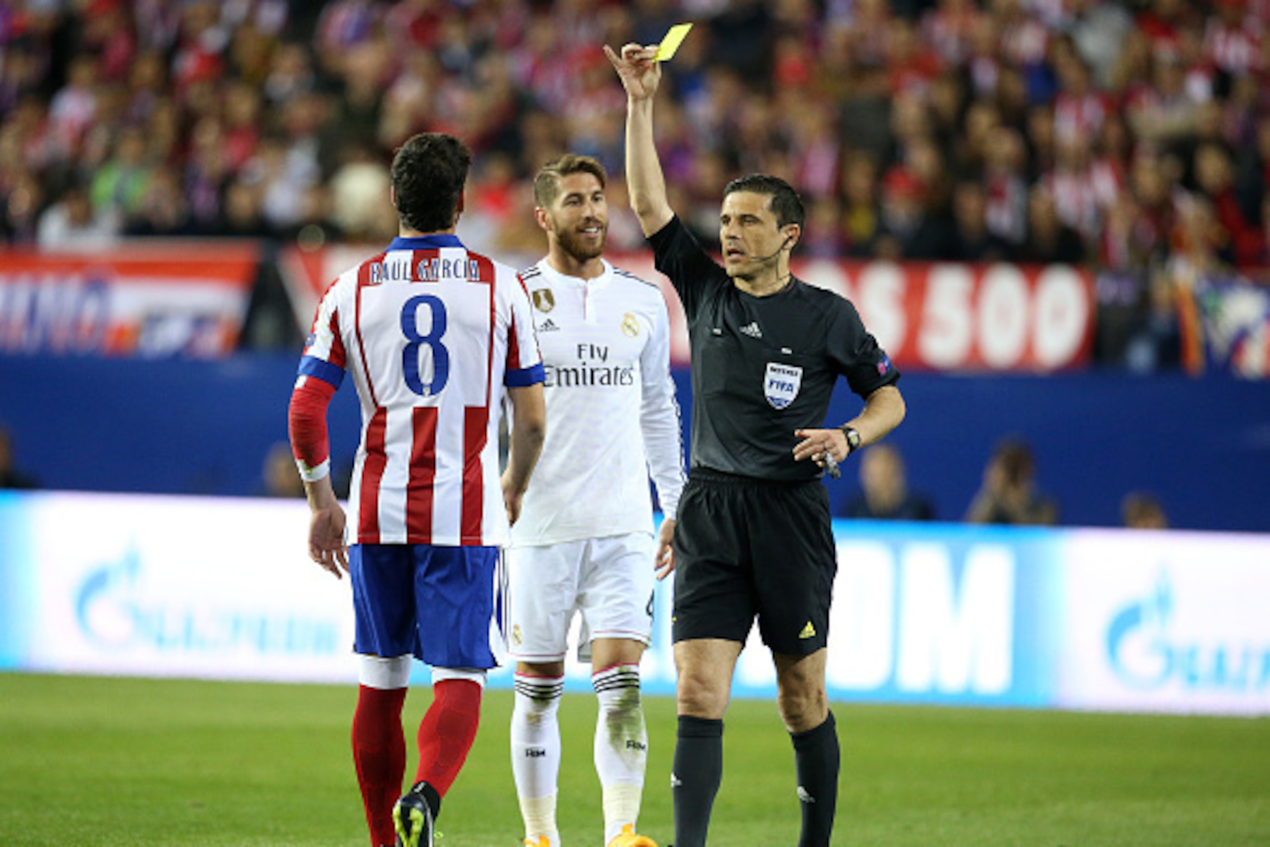 MADRID, SPAIN - APRIL 14:  Raul Garcia Escudero of Atletico Madrid (L) is shown a yellow card by referee Milorad Mazic of Serbia during the UEFA Champions League Quarter Final First Leg match between Atletico Madrid and Real Madrid at Vicente Calderon sta