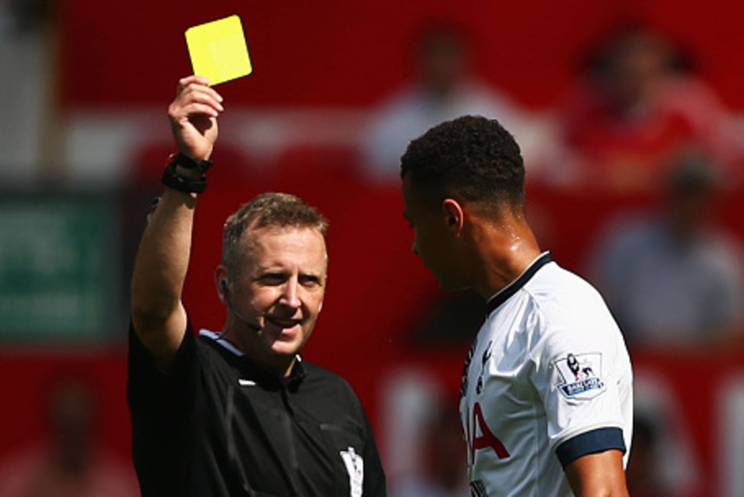 MANCHESTER, ENGLAND - AUGUST 08: Dele Alli of Tottenham Hotspur is shown a yellow card by referee Jonathan Moss during the Barclays Premier League match between Manchester United and Tottenham Hotspur at Old Trafford on August 8, 2015 in Manchester, Engla