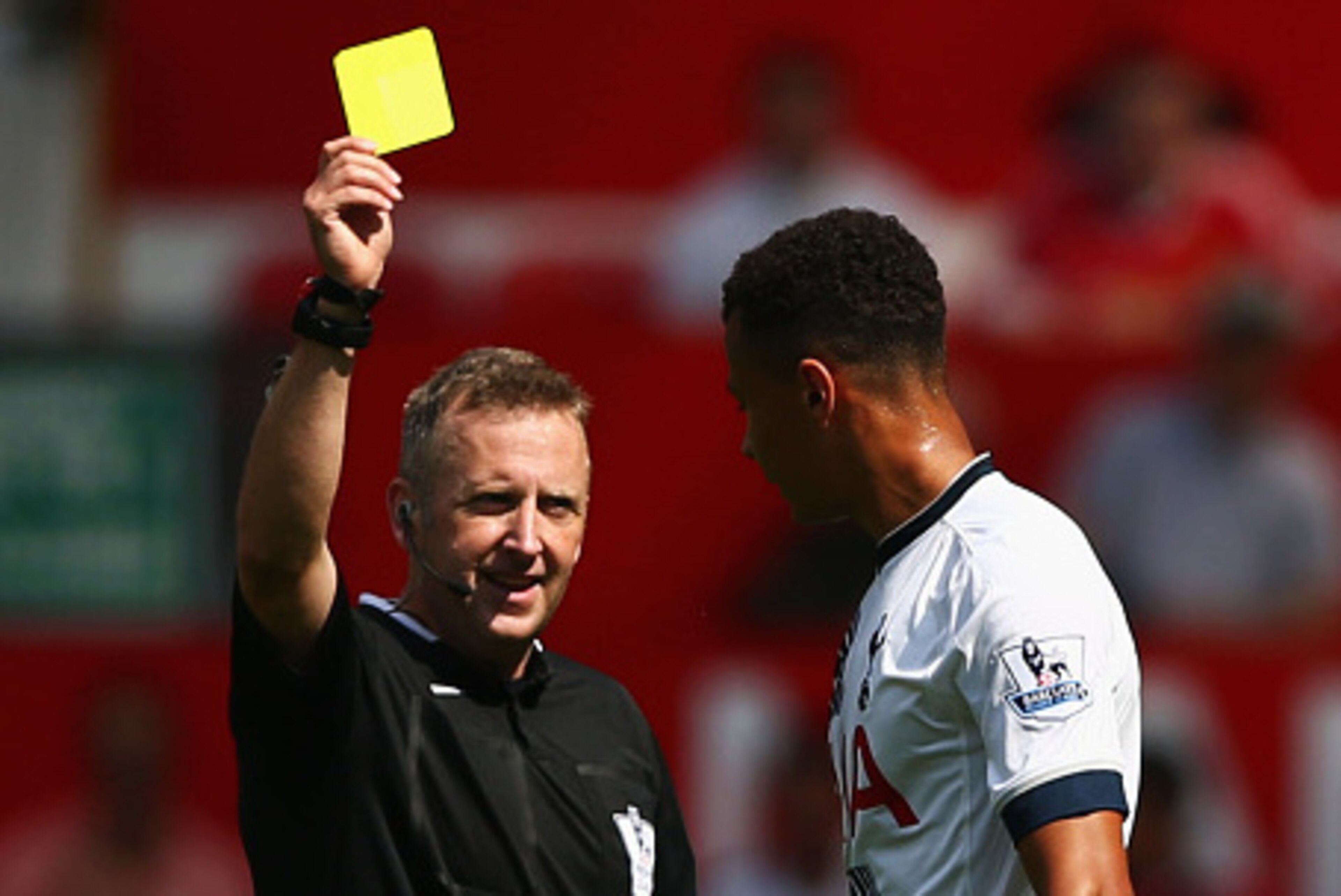 MANCHESTER, ENGLAND - AUGUST 08: Dele Alli of Tottenham Hotspur is shown a yellow card by referee Jonathan Moss during the Barclays Premier League match between Manchester United and Tottenham Hotspur at Old Trafford on August 8, 2015 in Manchester, Engla