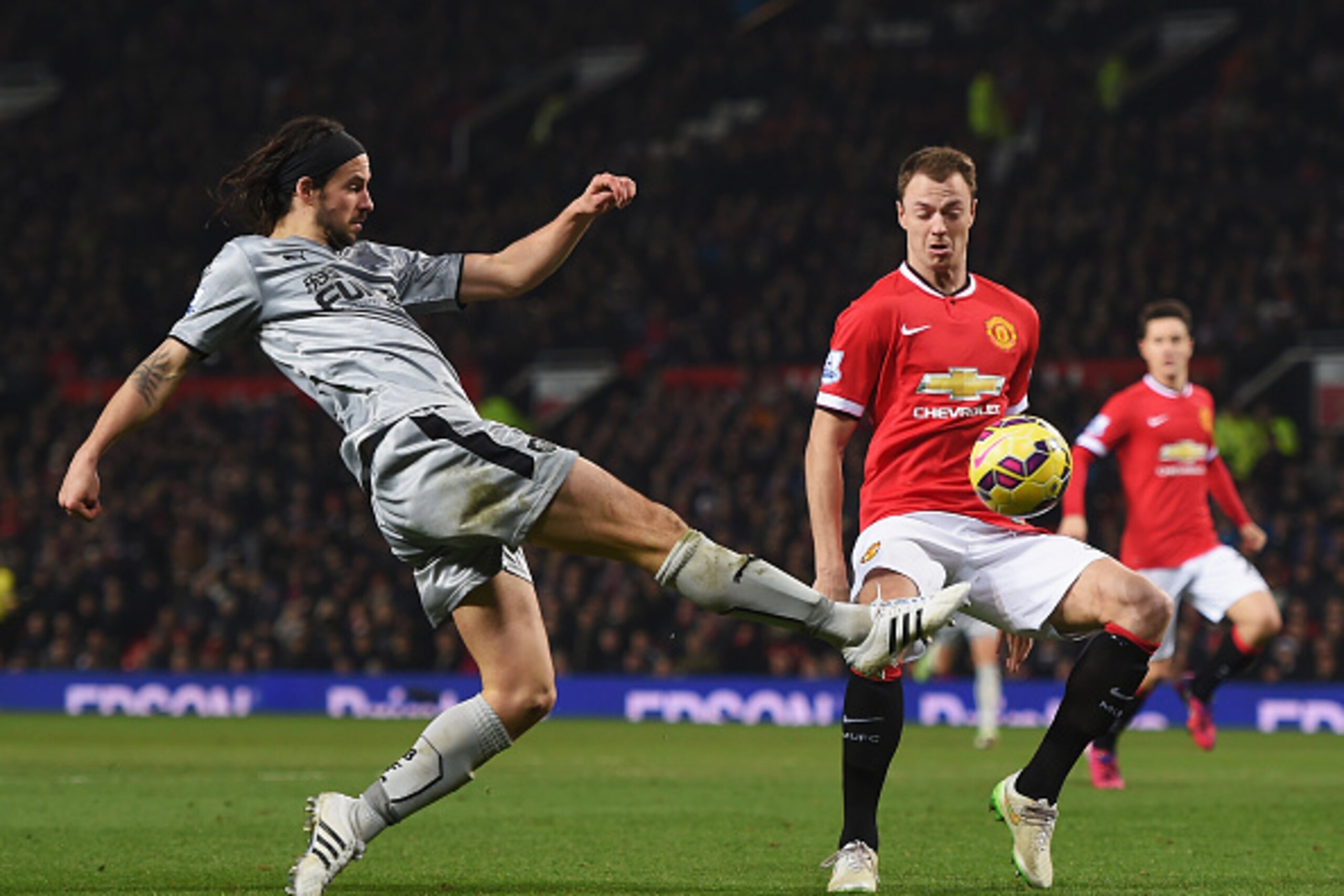 MANCHESTER, ENGLAND - FEBRUARY 11:  George Boyd of Burnley shoots as he is closed down by Jonny Evans of Manchester United during the Barclays Premier League match between Manchester United and Burnley at Old Trafford on February 11, 2015 in Manchester, E