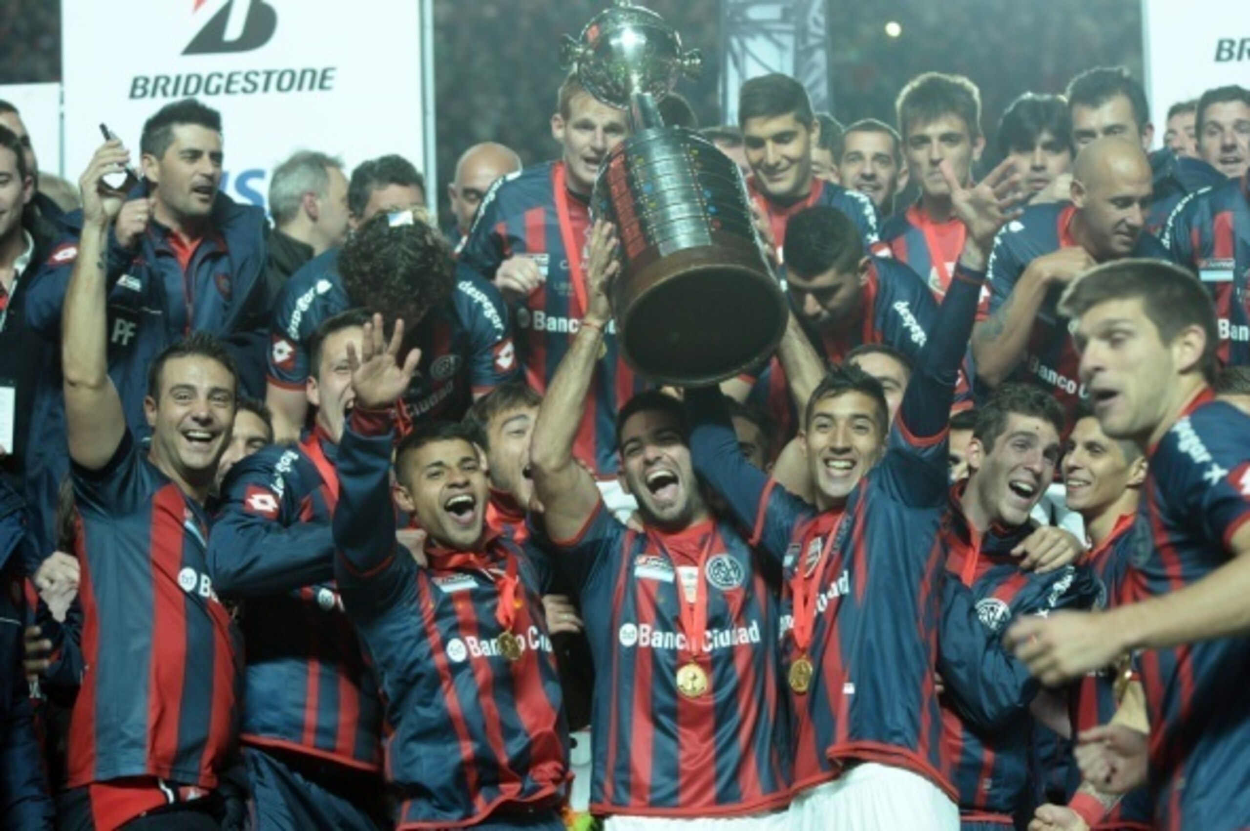 Argentina's San Lorenzo players hold up the Libertadores Cup after winning the second leg final football match against Paraguay's Nacional, at the Pedro Bidegain stadium in Buenos Aires, on August 13, 2014. AFP PHOTO        (Photo credit should read STR/A