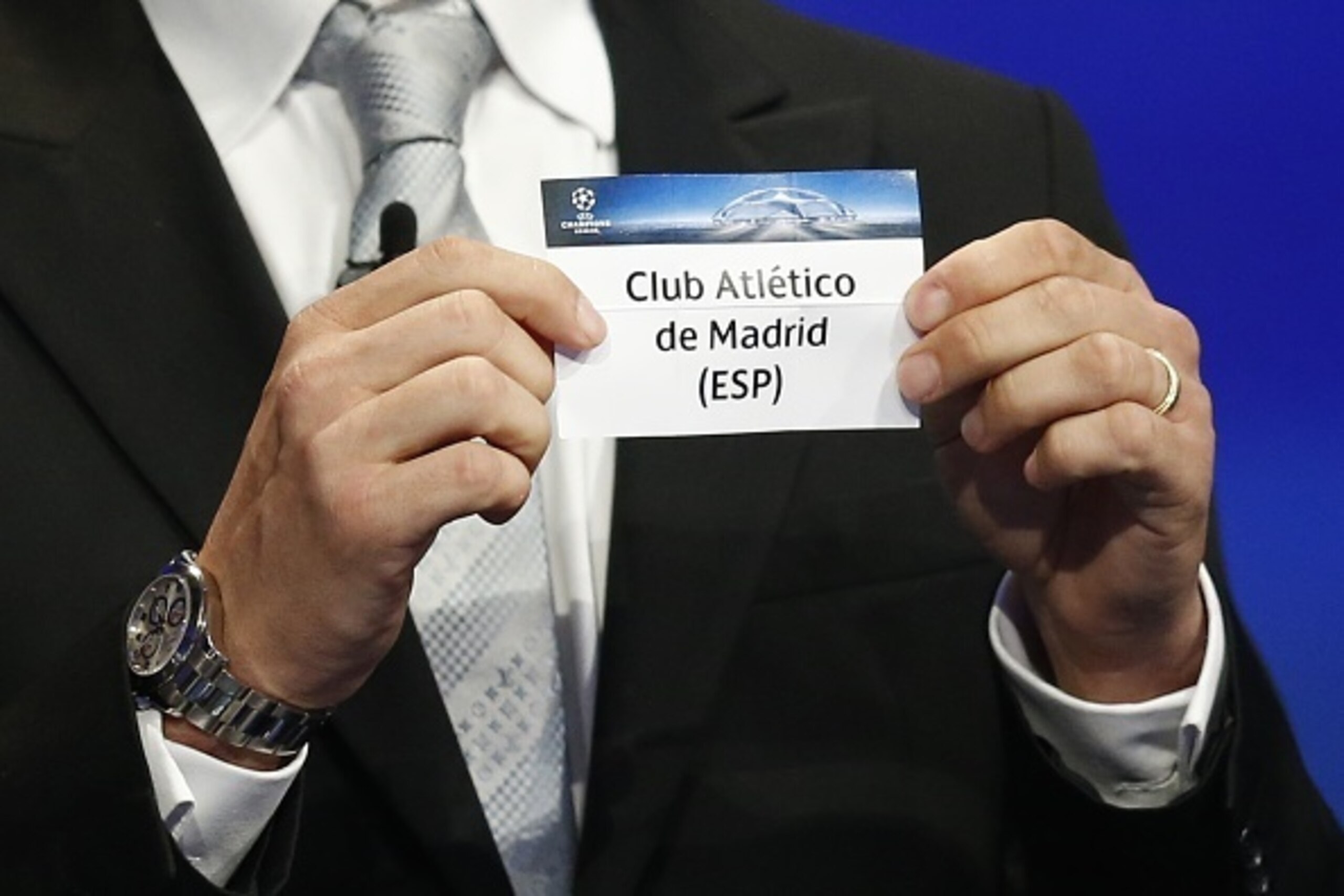 Former Brazilian football player Juliano Belletti shows the name of Atletico Madrid football club during the UEFA Champions League Group stage draw ceremony, on August 27, 2015 in Monaco. AFP PHOTO / VALERY HACHE        (Photo credit should read VALERY HA
