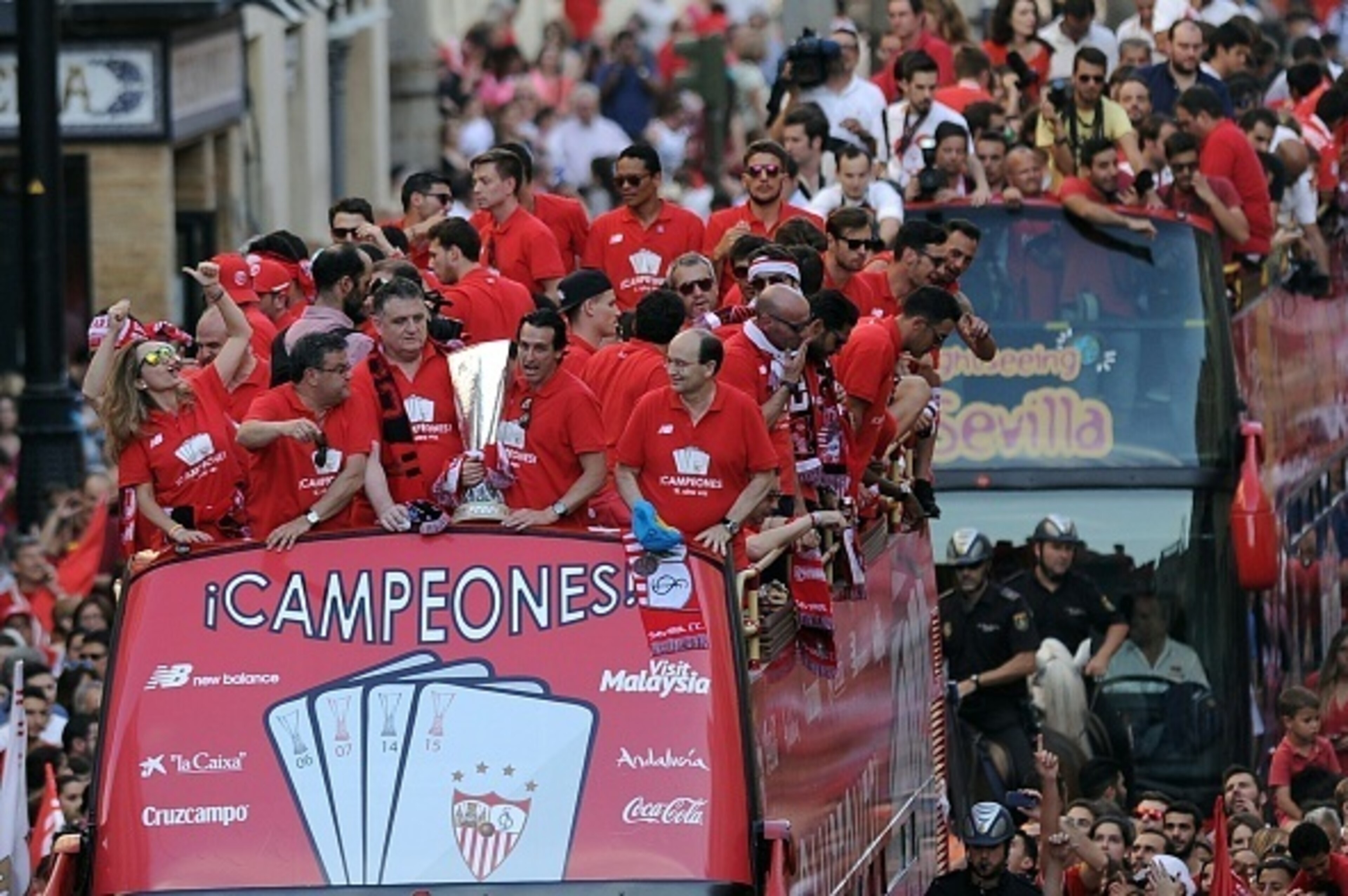 Sevilla Football Club team parade on top of a bus by a street of Sevilla to celebrate their victory in the UEFA Europa League final football match between FC Dnipro Dnipropetrovsk and Sevilla FC on May 28, 2015 in Sevilla.  AFP PHOTO / CRISTINA QUICLER   