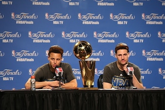 CLEVELAND, OH - JUNE 16:  Stephen Curry #30 and Klay Thompson #11 of the Golden State Warriors with the Larry O'Brien Championship Trophy at the post game press conference after Game Six of the 2015 NBA Finals against the Cleveland Cavaliers on June 16, 2