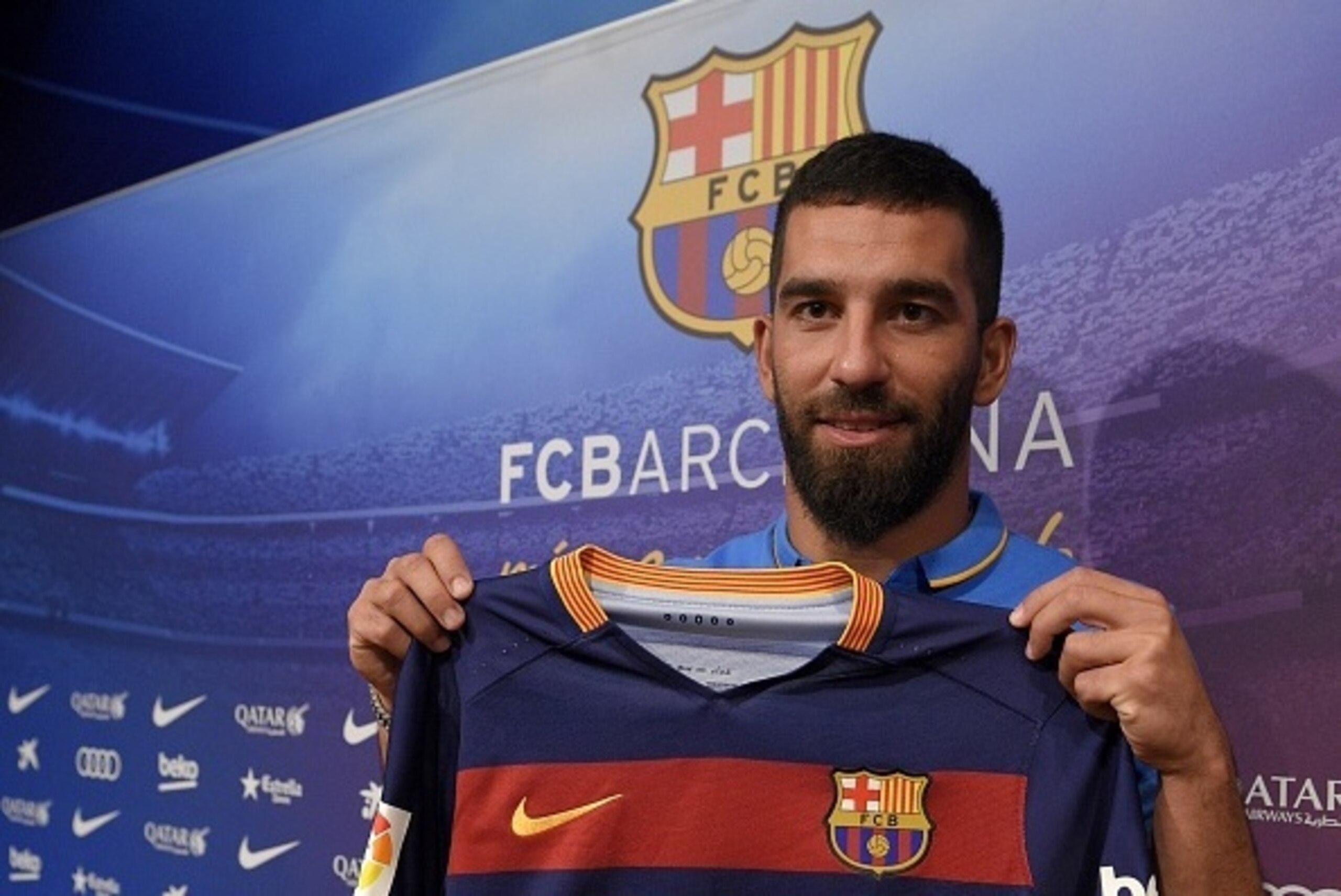 Barcelona's new player Turkish Arda Turan shows his new jersey at the Camp Nou stadium in Barcelona, after signing his new contract with the Catalan club, on July 10, 2015. Barcelona will keep more than 60 million euros ($65 million) of talent on the side