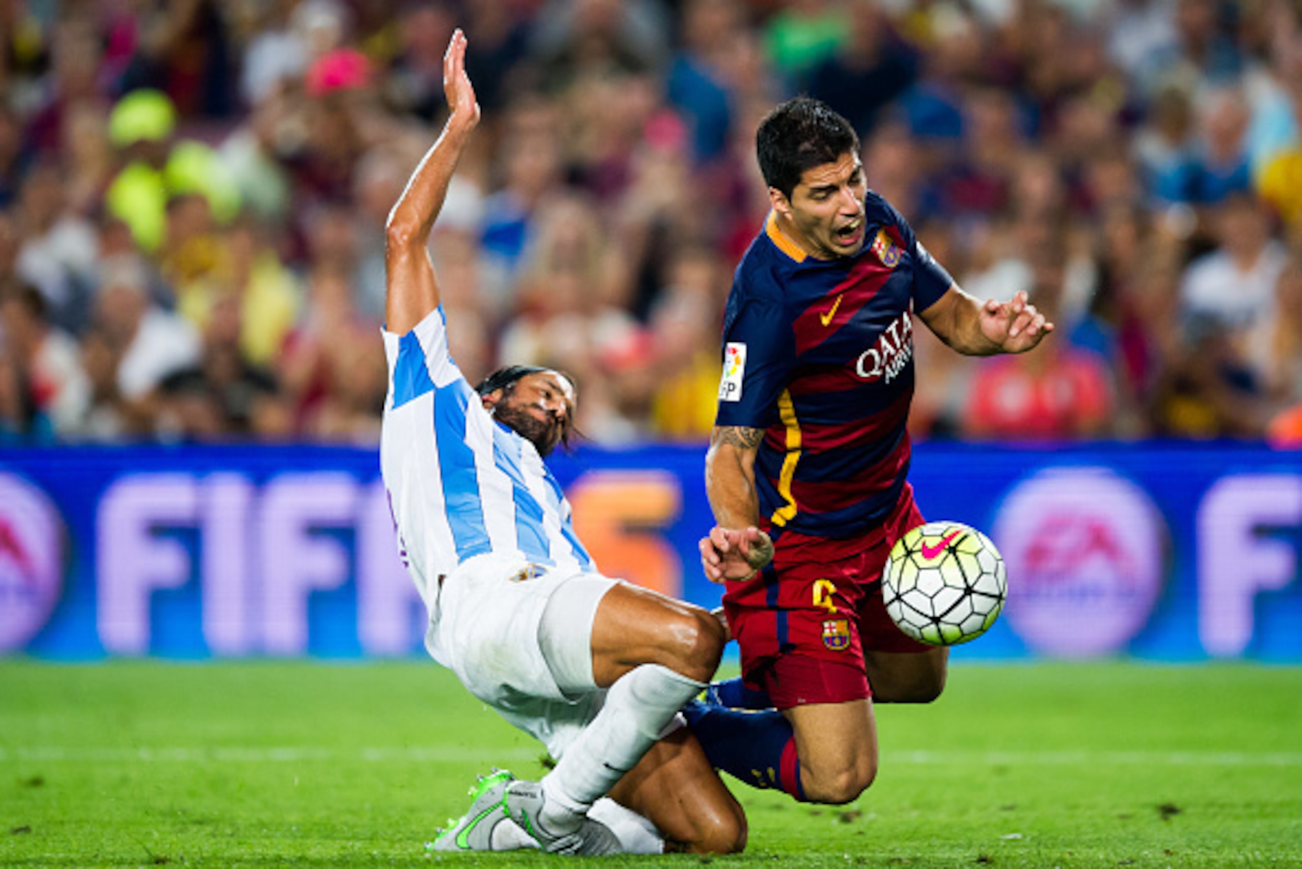BARCELONA, SPAIN - AUGUST 29:  Luis Suarez of FC Barcelona is brought down by Marcos Angeleri of Malaga CF during the La Liga match between FC Barcelona and Malaga CF at Camp Nou on August 29, 2015 in Barcelona, Spain.  (Photo by Alex Caparros/Getty Image