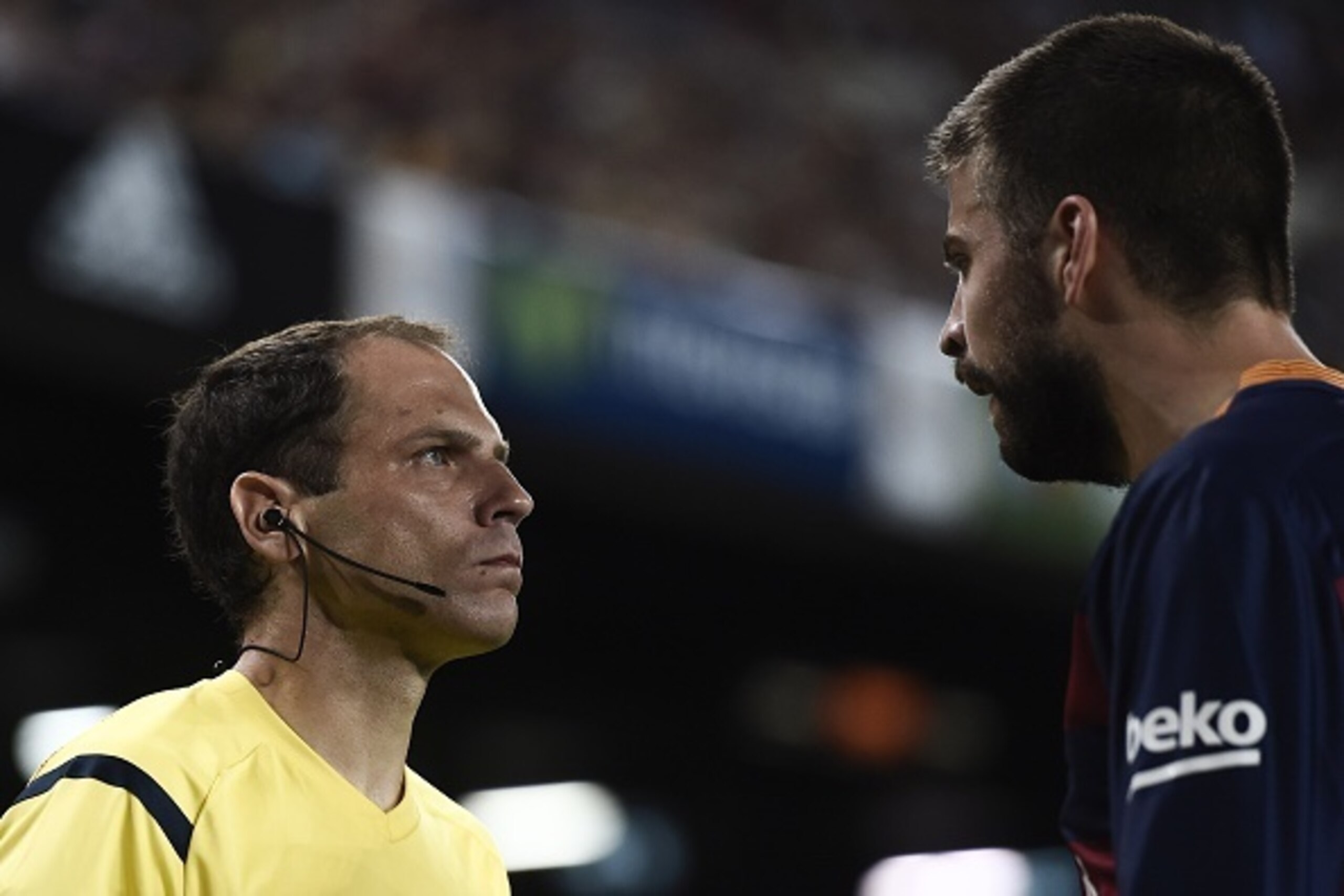 An assistant referee looks at Barcelona's defender Gerard Pique (R) during the Spanish Supercup second-leg football match FC Barcelona vs Athletic club Bilbao at the Camp Nou stadium in Barcelona on August 17, 2015. AFP PHOTO / JOSEP LAGO        (Photo cr