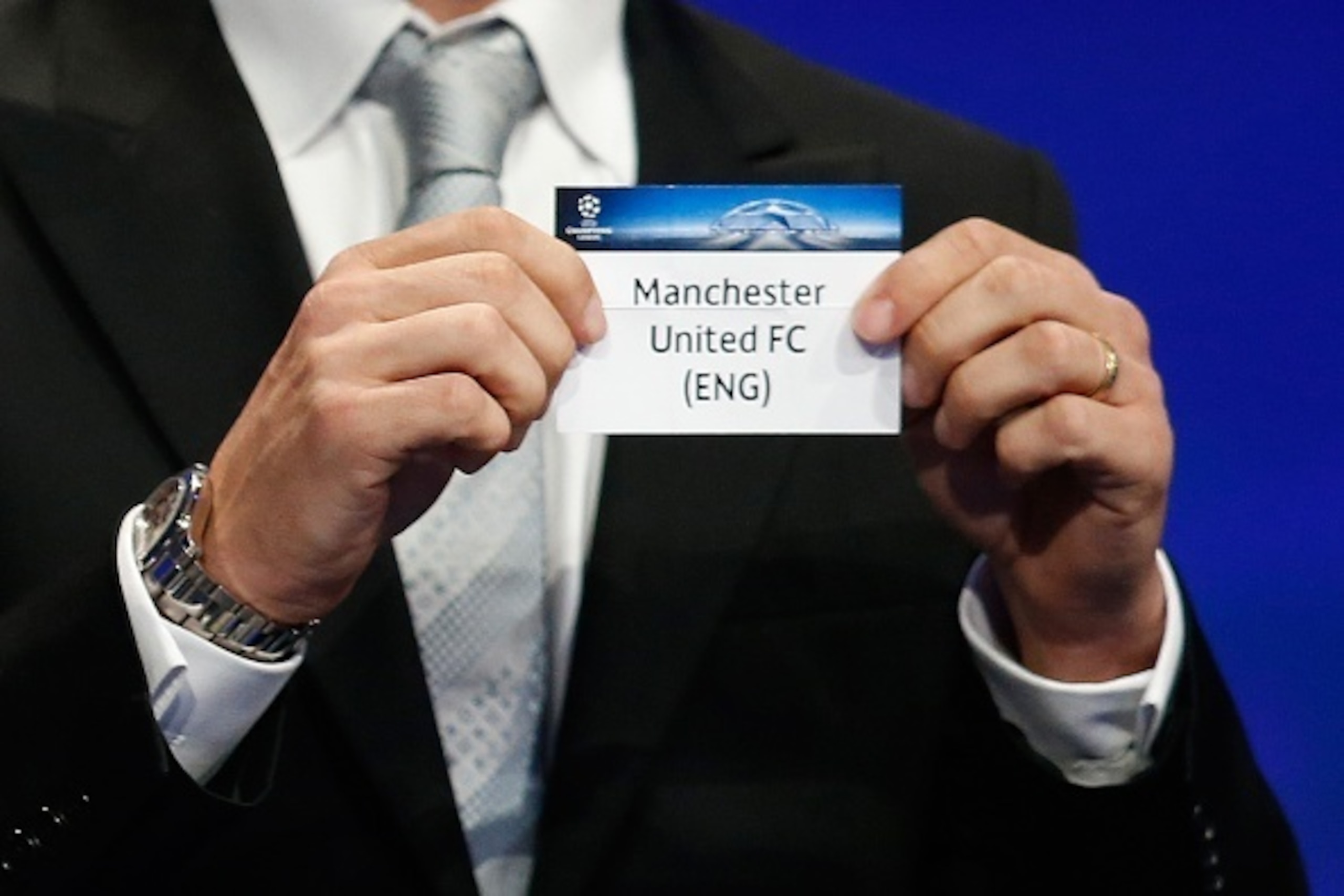 Former Brazilian football player Juliano Belletti shows the name of Manchester United football club during the UEFA Champions League Group stage draw ceremony, on August 27, 2015 in Monaco. AFP PHOTO / VALERY HACHE        (Photo credit should read VALERY 