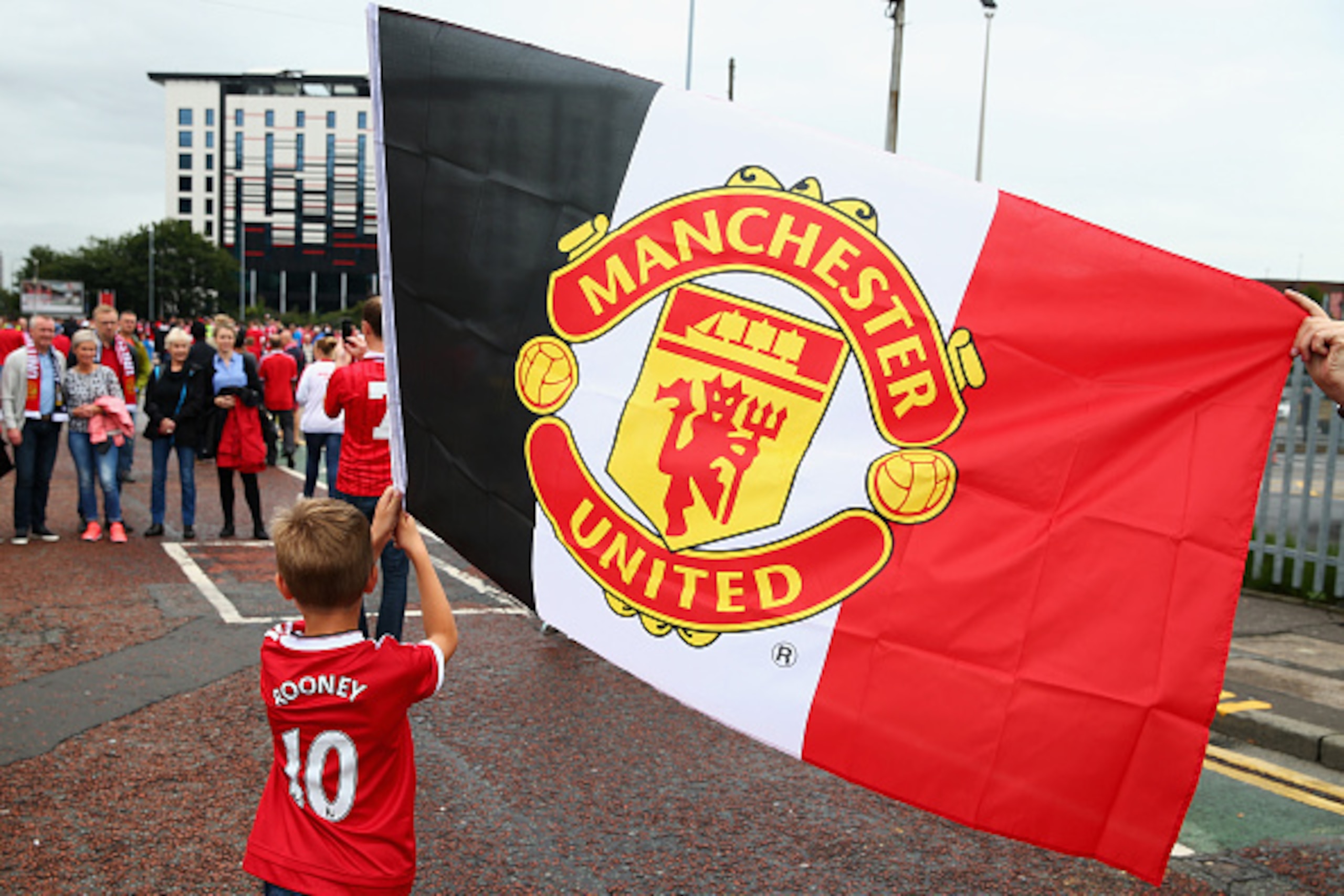 MANCHESTER, ENGLAND - AUGUST 22:  A yonng Manchester United fan waves a Manchester United flag prior to the Barclays Premier League match between Manchester United and Newcastle United at Old Trafford on August 22, 2015 in Manchester, England.  (Photo by 