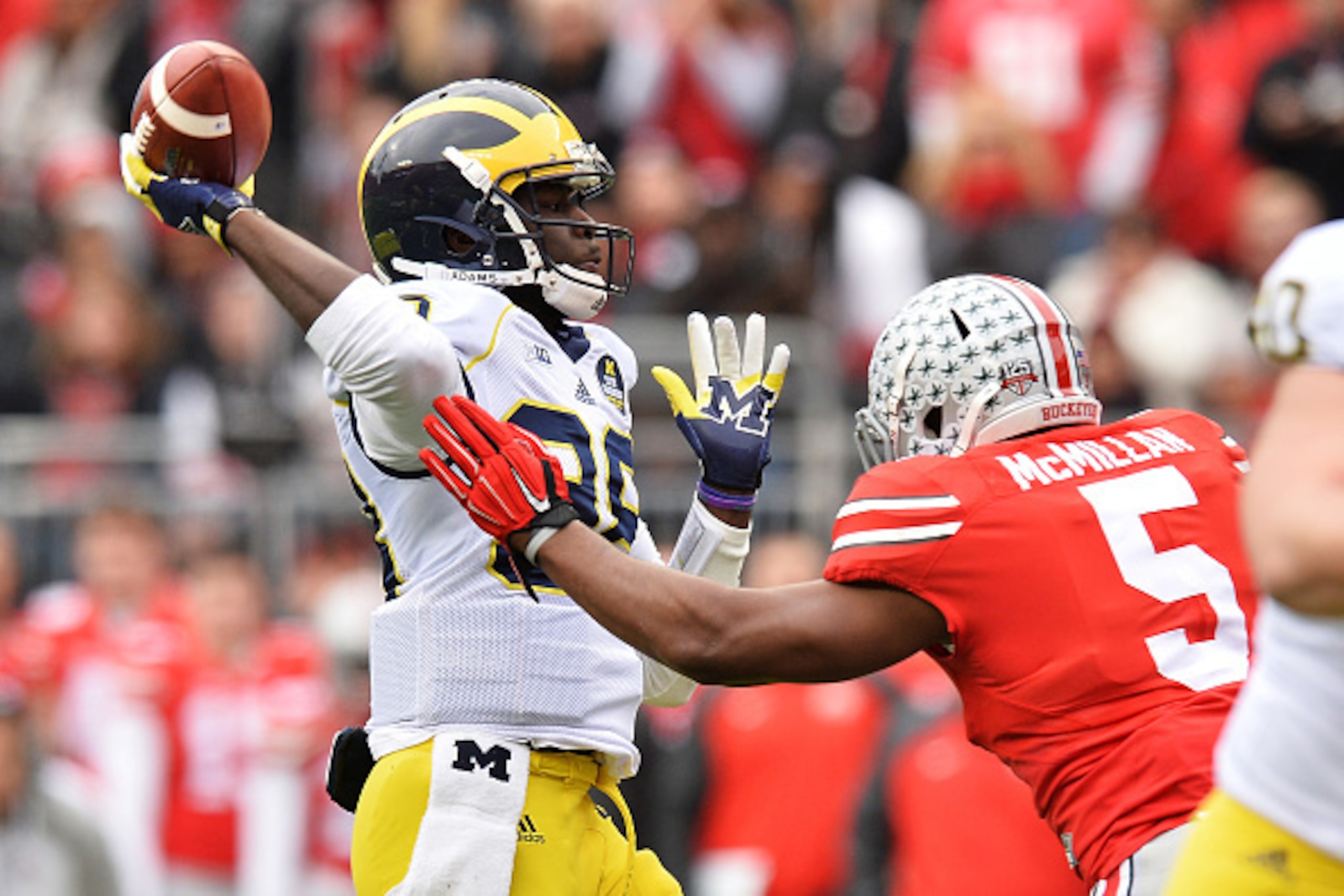 COLUMBUS, OH - NOVEMBER 29:  Quarterback Devin Gardner #98 of the Michigan Wolverines tosses a 12-yard touchdown pass as he is rushed by Raekwon McMillan #5 of the Ohio State Buckeyes in the first quarter at Ohio Stadium on November 29, 2014 in Columbus, 