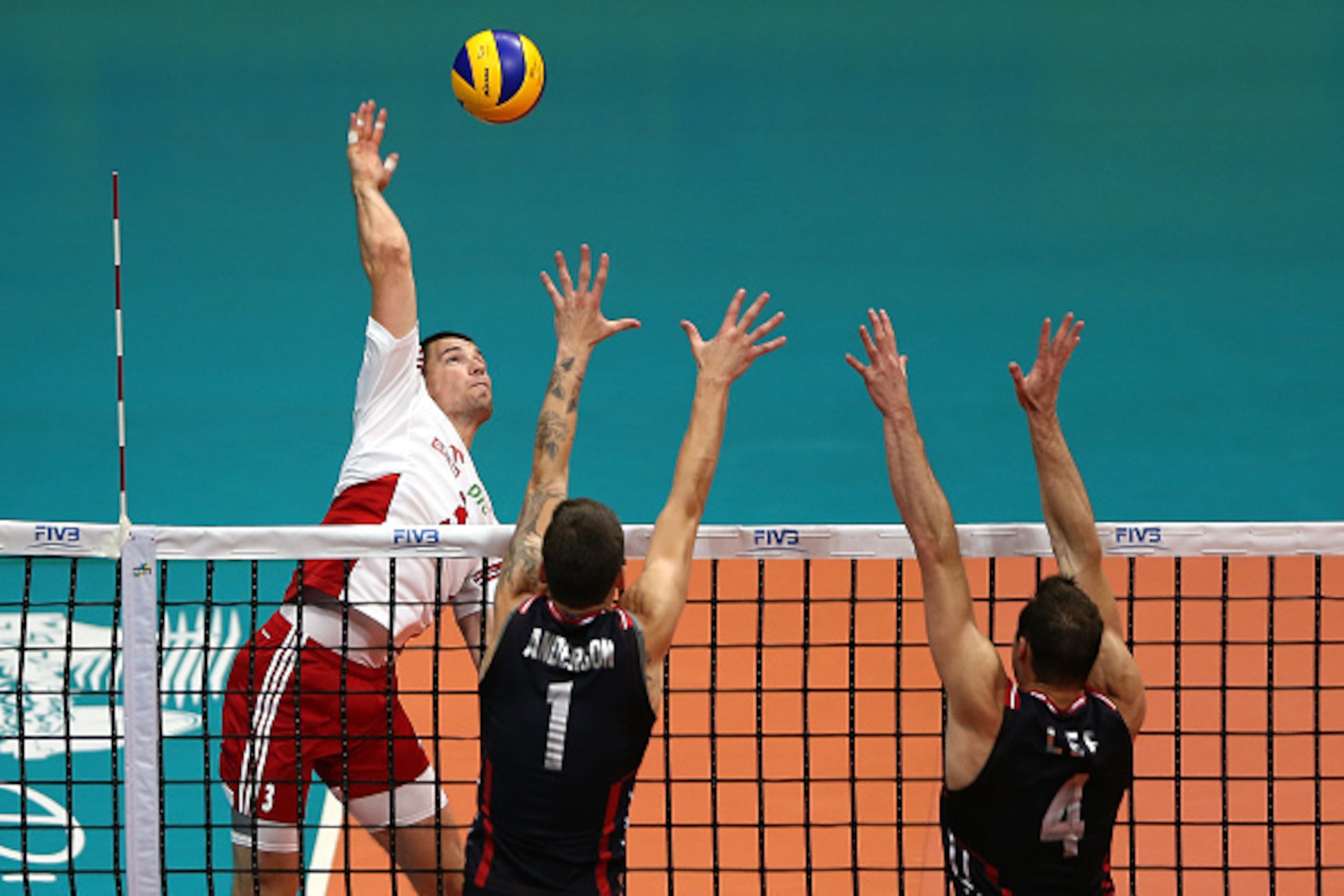 RIO DE JANEIRO, BRAZIL - JULY 19:  Dawid Konarski of Poland spikes the ball against (L-R) Matthew Anderson and David Lee of the Unites States during the FIVB World League Group 1 Finals third place match between the United States and Poland at Maracanazin