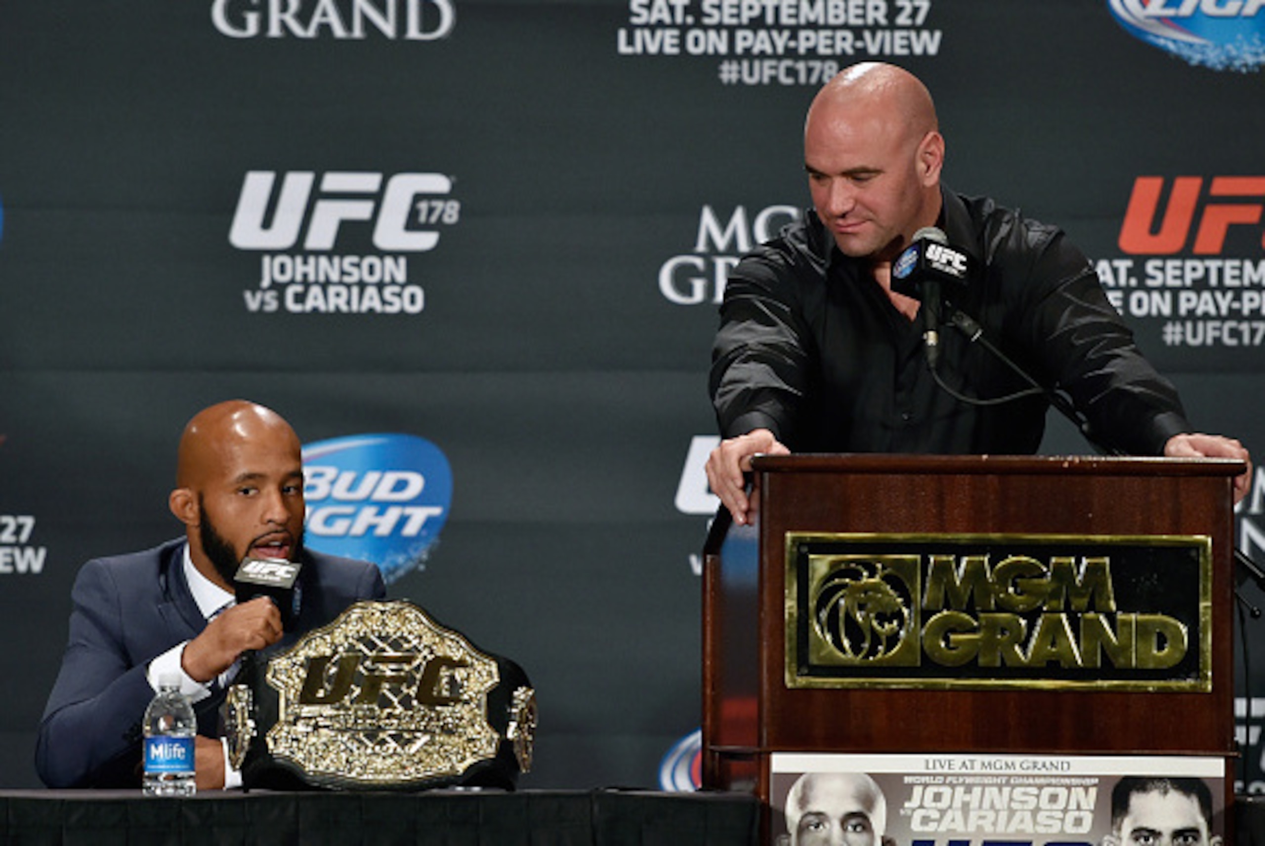 LAS VEGAS, NV - SEPTEMBER 27:  (L-R) UFC flyweight champion Demetrious 'Mighty Mouse' Johnson speaks to the media as UFC President Dana White looks down at him during the UFC 178 post fight press conference inside the MGM Grand Hotel/Casino on September 2