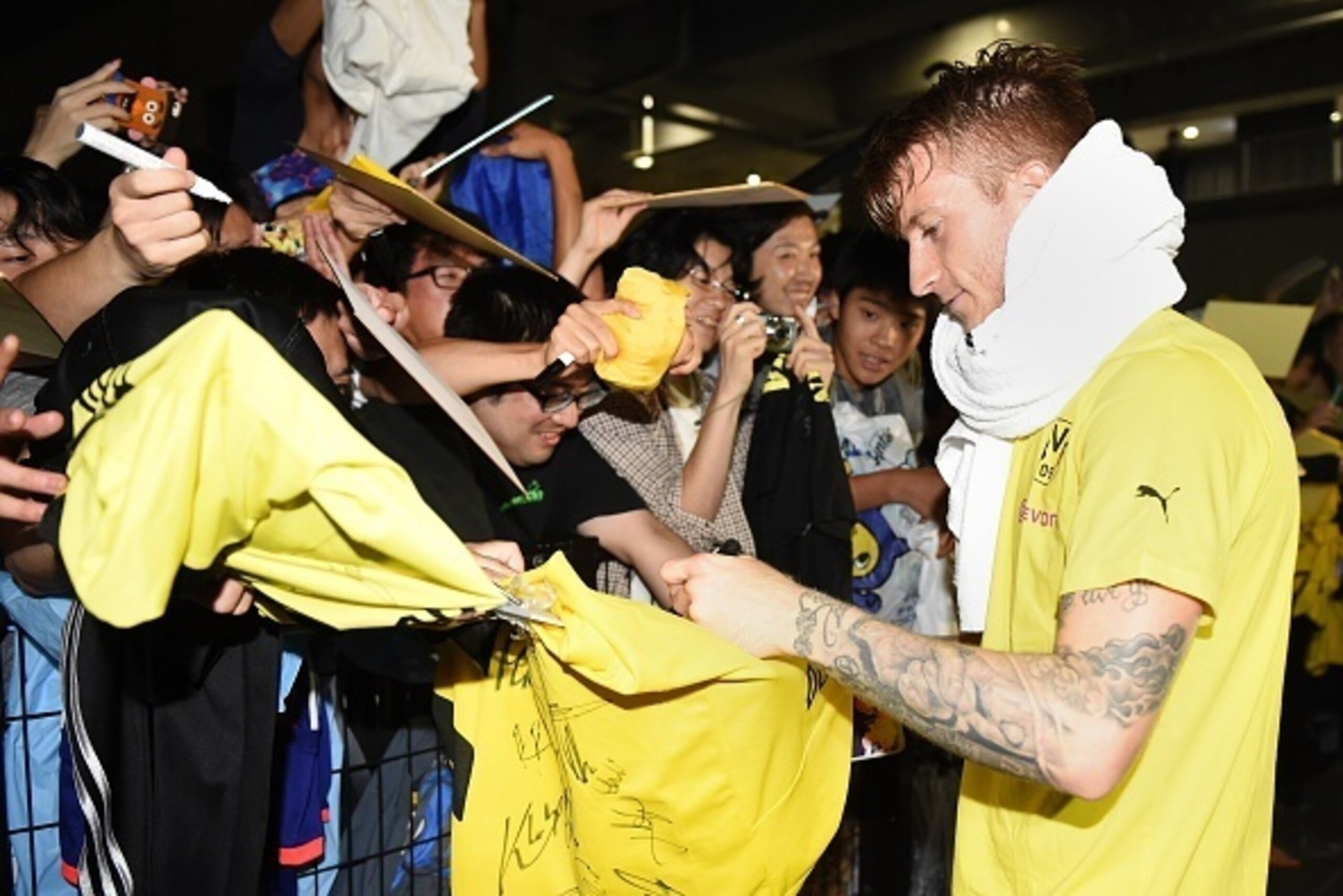 Forward Marco Reus (R) of Germany's football club Borussia Dortmund signs autographs to his Japanese fans after a training session after their arrival in Japan in Kawasaki, suburb of Tokyo on July 6, 2015.  Borussia Dortmund will play a friendly match wit