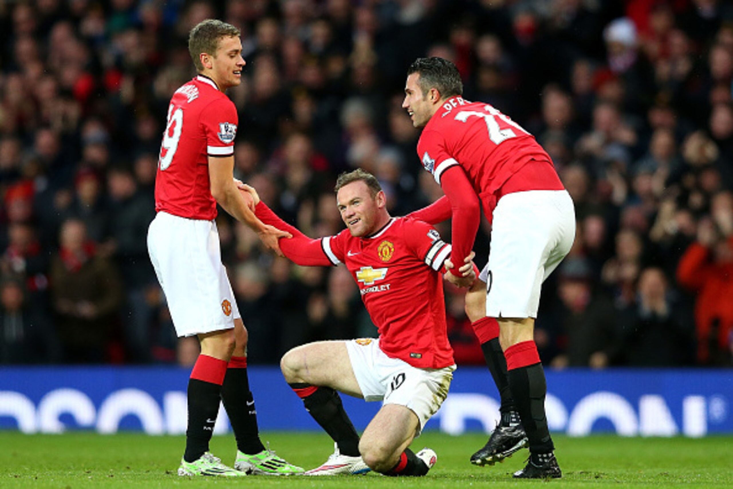 MANCHESTER, ENGLAND - DECEMBER 14:  Wayne Rooney of Manchester United is helped to his feet by James Wilson (L) and Robin van Persie (R) after scoring the first goal during the Barclays Premier League match between Manchester United and Liverpool at Old T