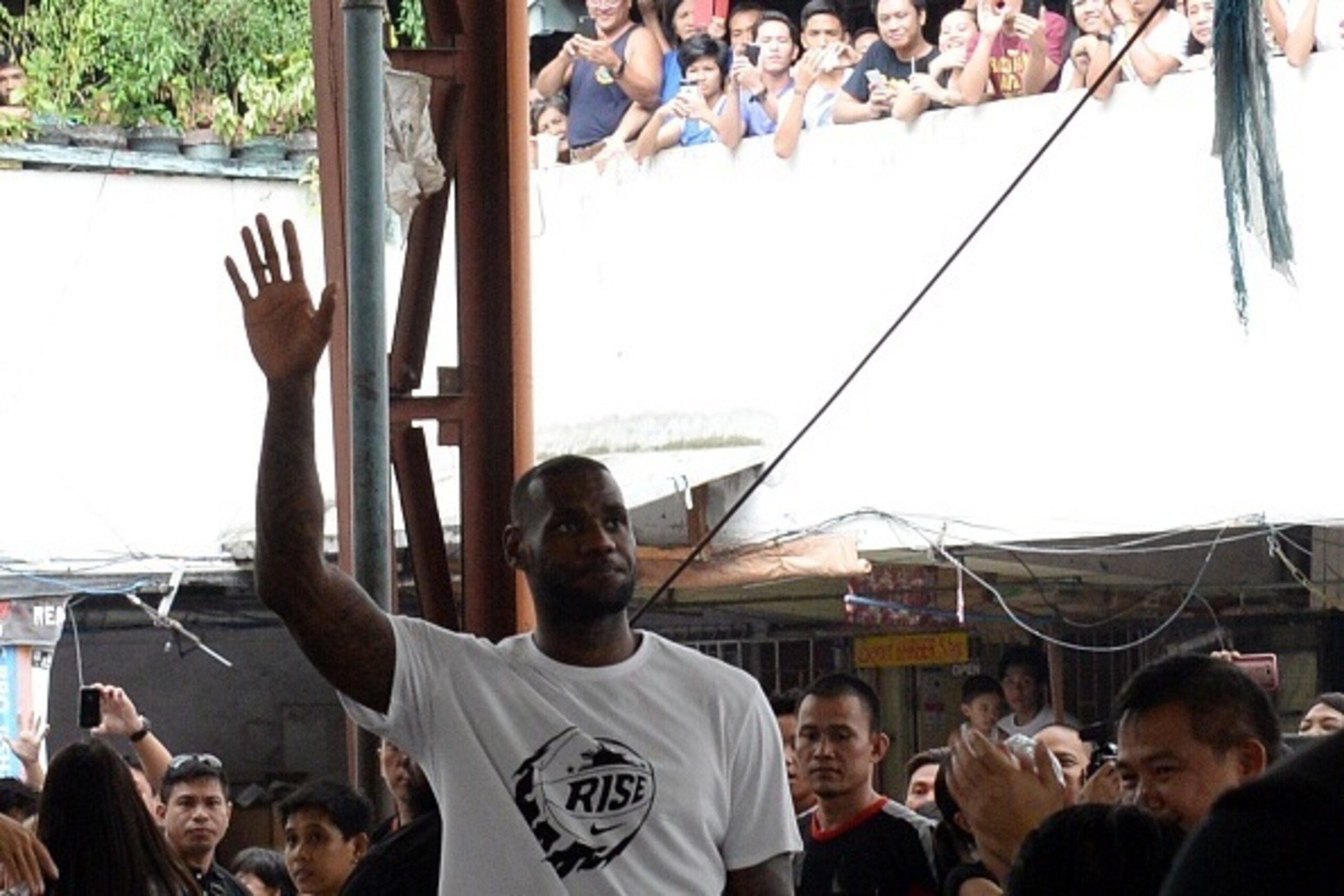 NBA superstar LeBron James of the US gestures as he visits a government mass housing project as part of the clinic session in Manila on August 21, 2015.  James is here to conduct basketball clinic to select talented basketball players from disadvantaged f