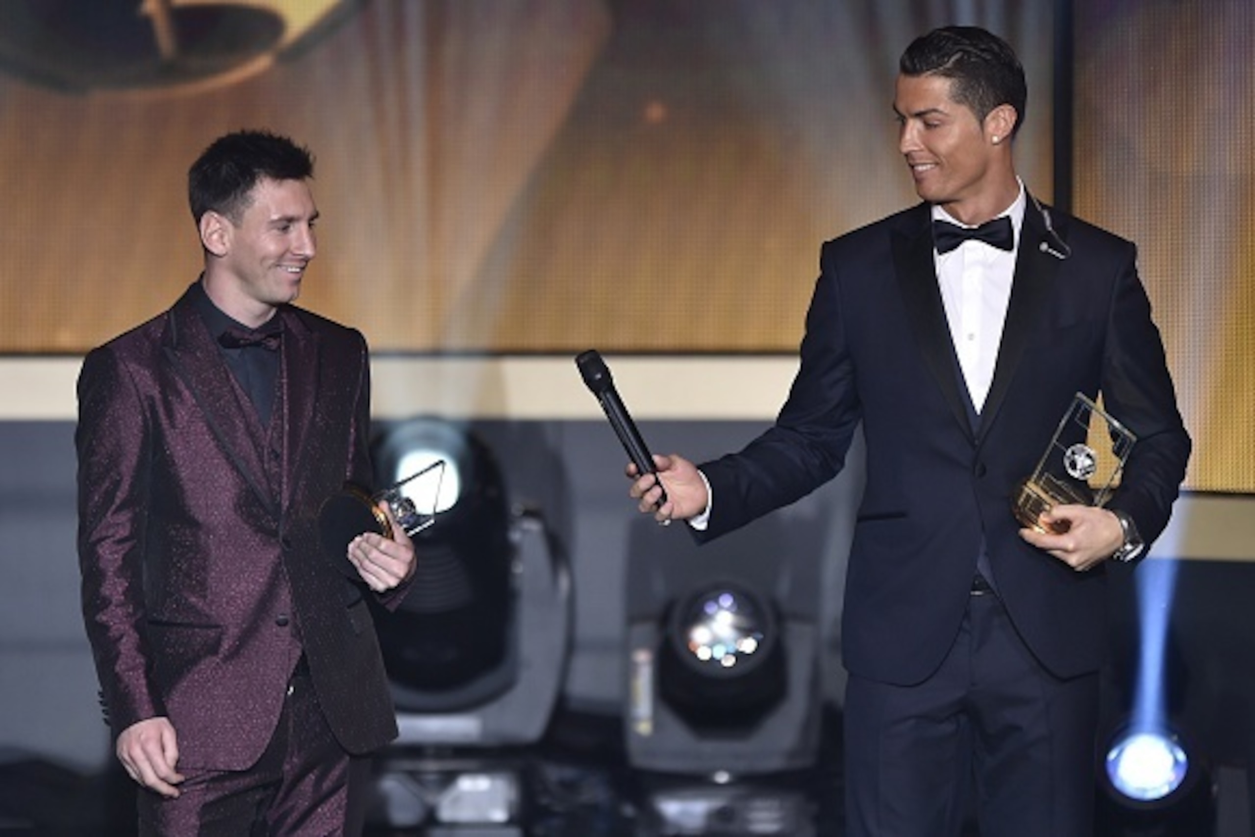 Real Madrid and Portugal forward Cristiano Ronaldo hands a microhpone to Barcelona and Argentina forward Lionel Messi (L) as they stand on stage after being selected in the 2014 FIFA FIFPro World XI during the FIFA Ballon d'Or award ceremony at the Kongre