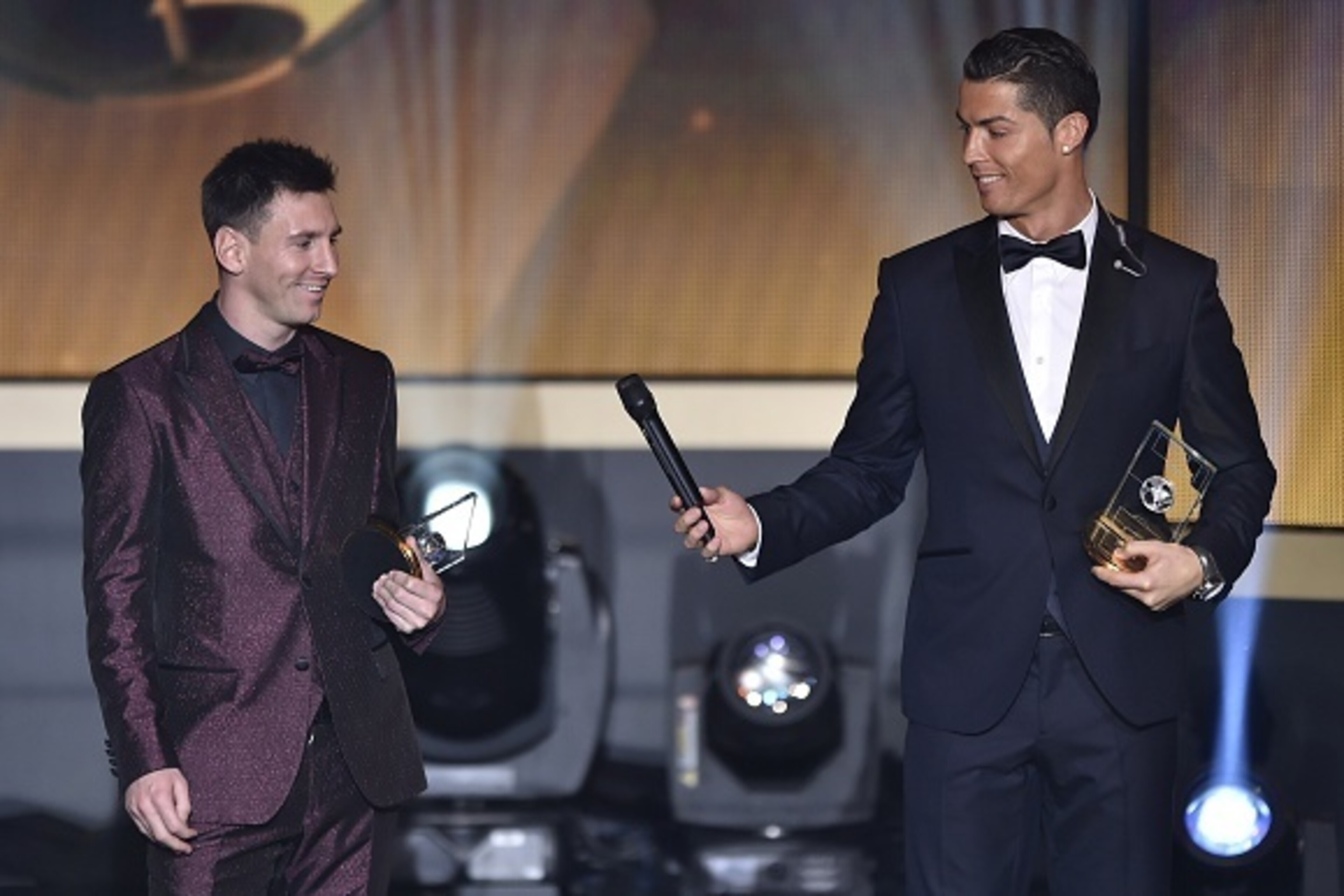 Real Madrid and Portugal forward Cristiano Ronaldo hands a microhpone to Barcelona and Argentina forward Lionel Messi (L) as they stand on stage after being selected in the 2014 FIFA FIFPro World XI during the FIFA Ballon d'Or award ceremony at the Kongre