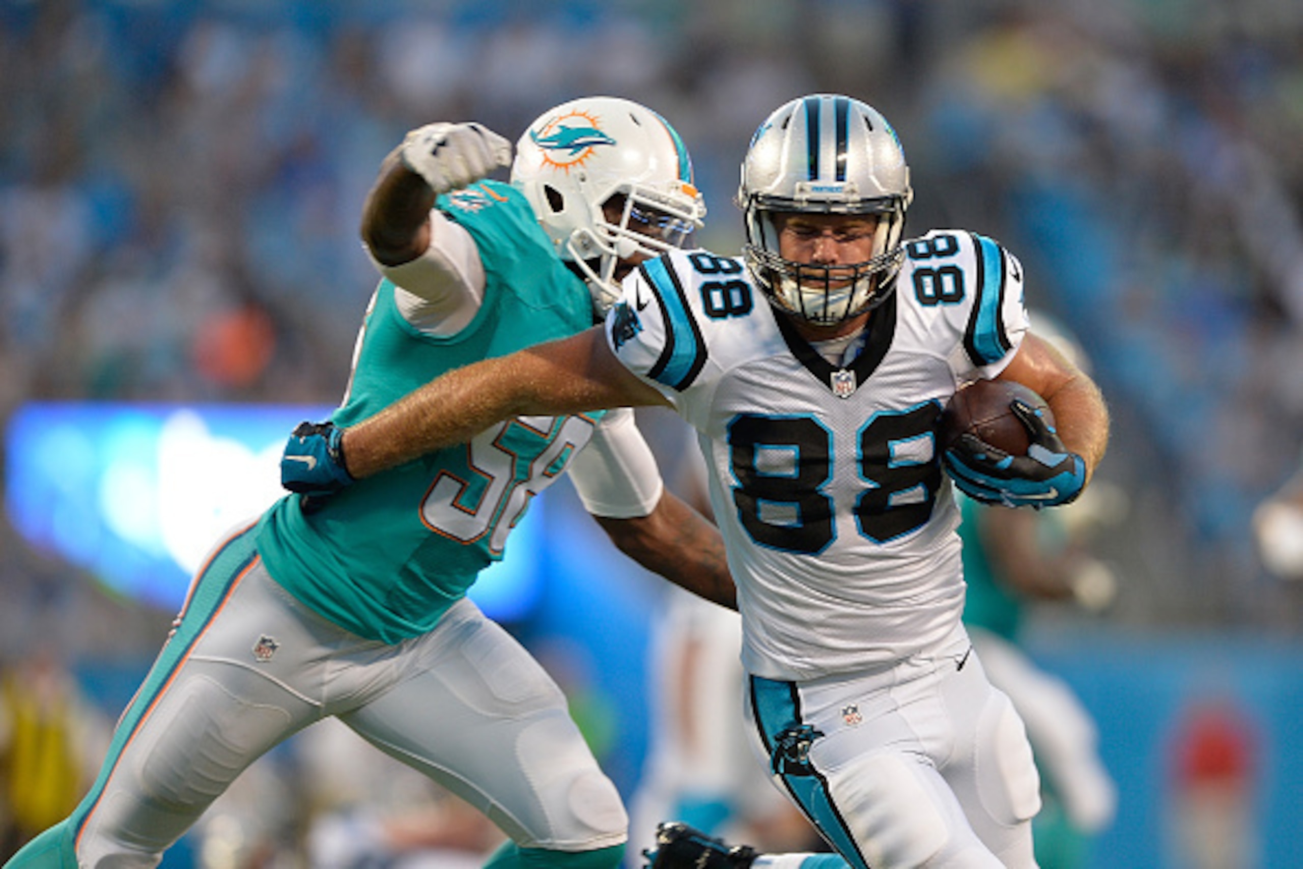 CHARLOTTE, NC - AUGUST 22:  Greg Olsen #88 of the Carolina Panthers makes a catch under pressure from Chris McCain #58 of the Miami Dolphins during their preseason NFL game at Bank of America Stadium on August 22, 2015 in Charlotte, North Carolina.  (Phot