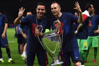 Barcelona's midfielder Xavi Hernandez (L) and Barcelona's midfielder Andres Iniesta celebrate with the trophy after the UEFA Champions League Final football match between Juventus and FC Barcelona at the Olympic Stadium in Berlin on June 6, 2015. FC Barce