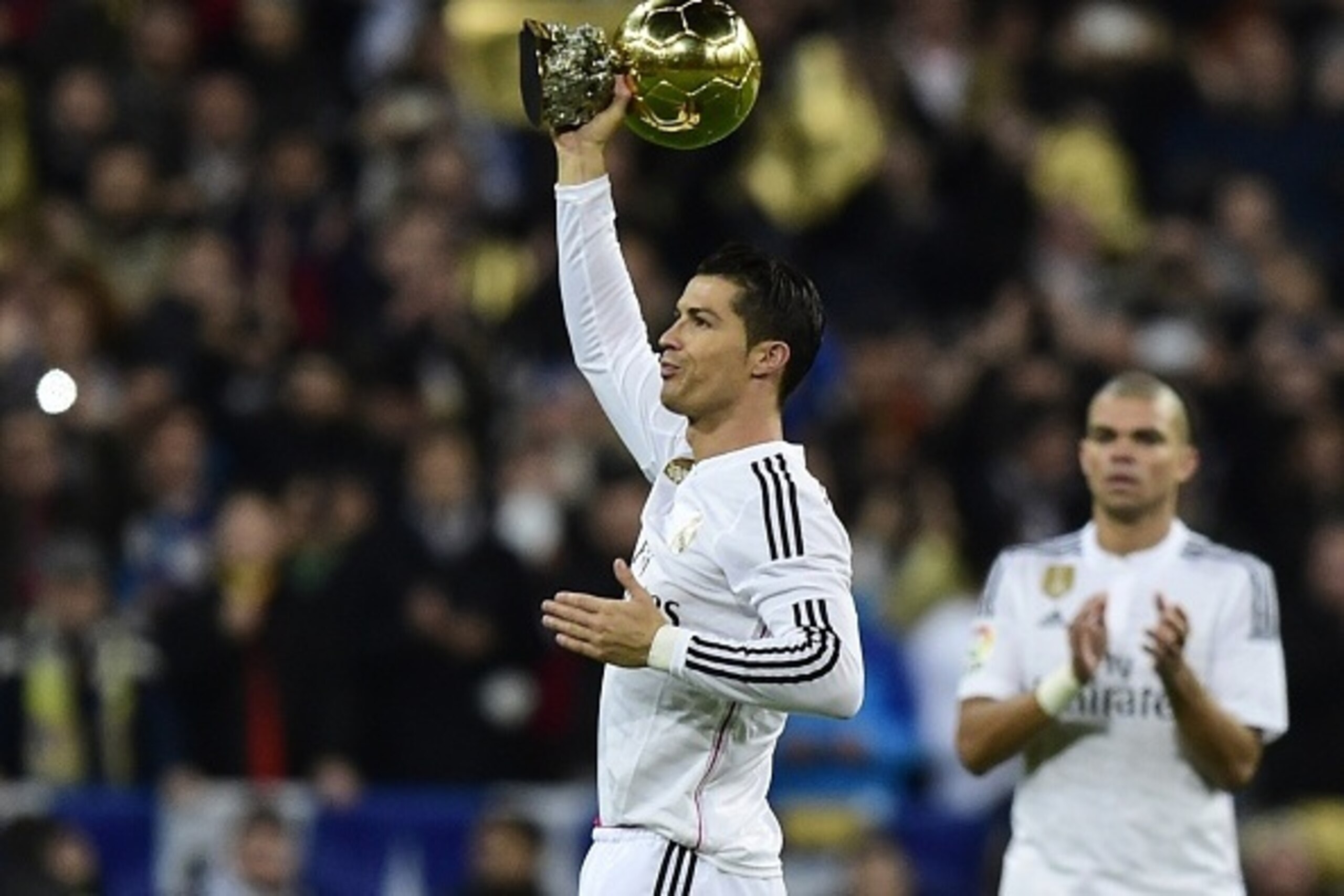 Real Madrid's Portuguese forward Cristiano Ronaldo shows the 2014 FIFA Ballon d'Or award for player of the year to his supporters prior to the Spanish Copa del Rey (King's Cup) round of 16 second leg football match Real Madrid CF vs Club Atletico de Madri