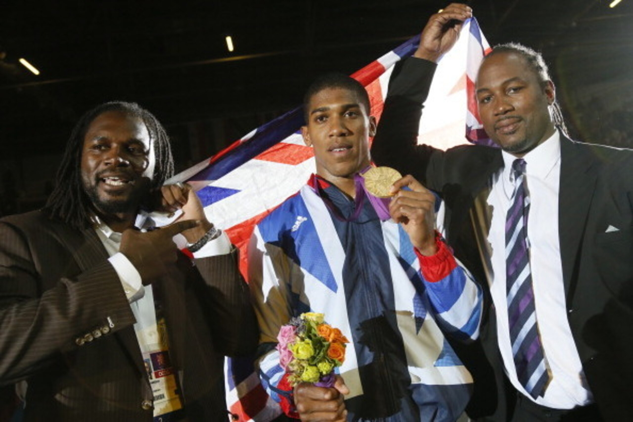 Gold medalist Anthony Joshua (C) celebrates with former world heavweight boxing champion fellow countryman Lennox Lewis (R) and British boxer Audley Harrison (L) during the awards ceremony for the Super-Heavyweight (+91kg) boxing category of the 2012 Lond
