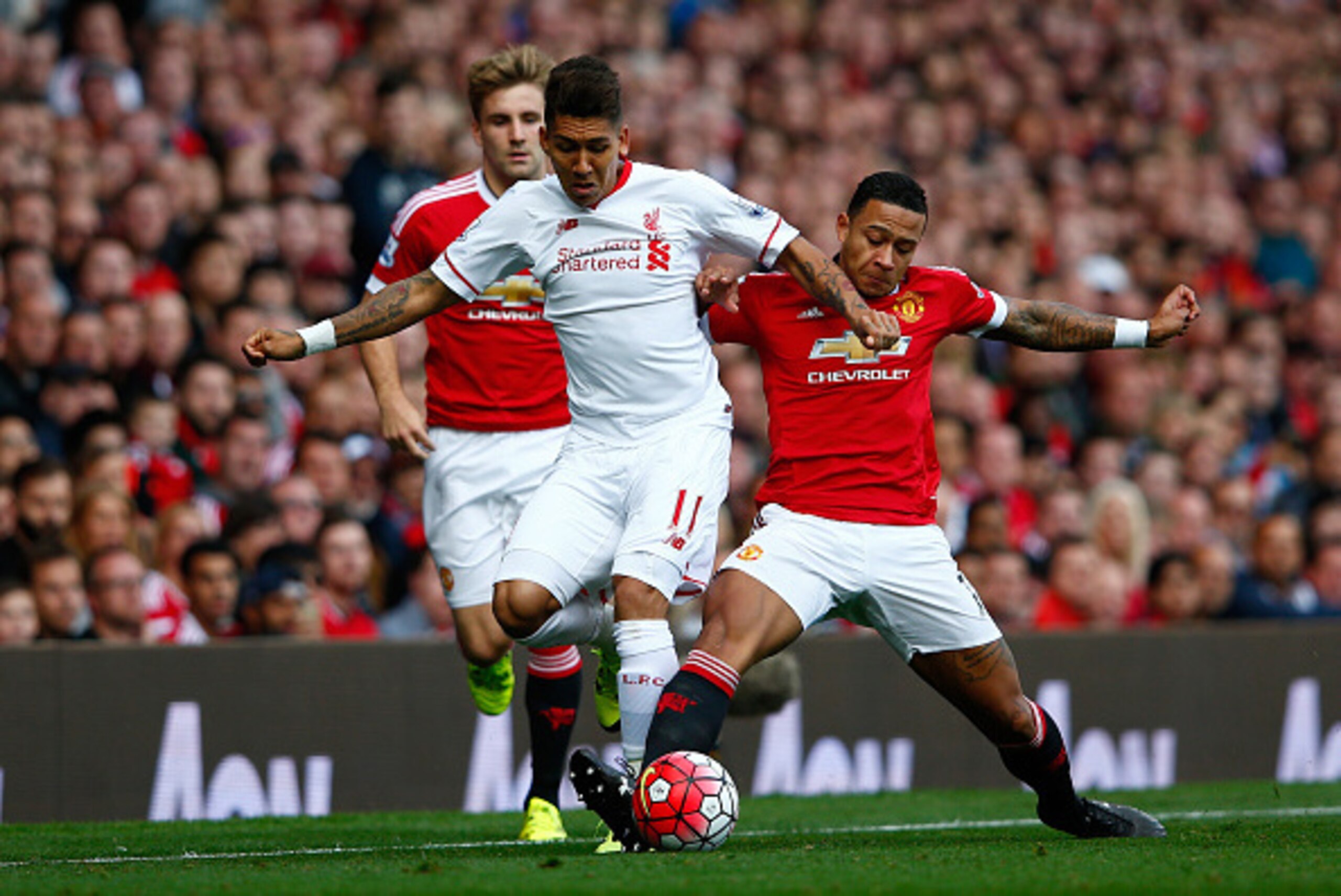 MANCHESTER, ENGLAND - SEPTEMBER 12: Roberto Firmino of Liverpool is challenged by Memphis Depay of Manchester United during the Barclays Premier League match between Manchester United and Liverpool at Old Trafford on September 12, 2015 in Manchester, Unit
