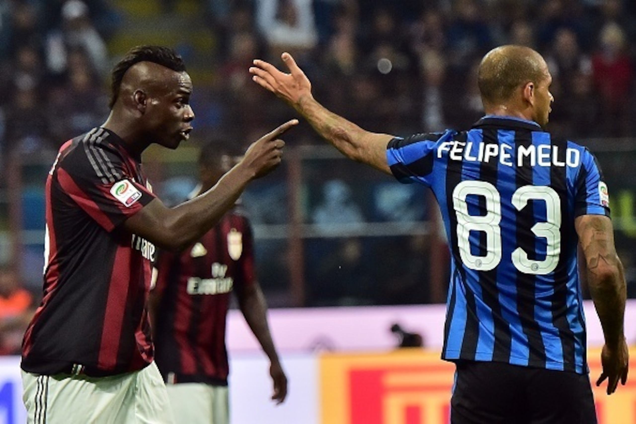 AC Milan's Italian forward Mario Balotelli (L) and Inter Milan's Brazilian midfielder Felipe Melo gesture during the Serie A football match between Inter Milan and AC Milan at San Siro Stadium in Milan on September 13, 2015 . AFP PHOTO / GIUSEPPE CACACE  