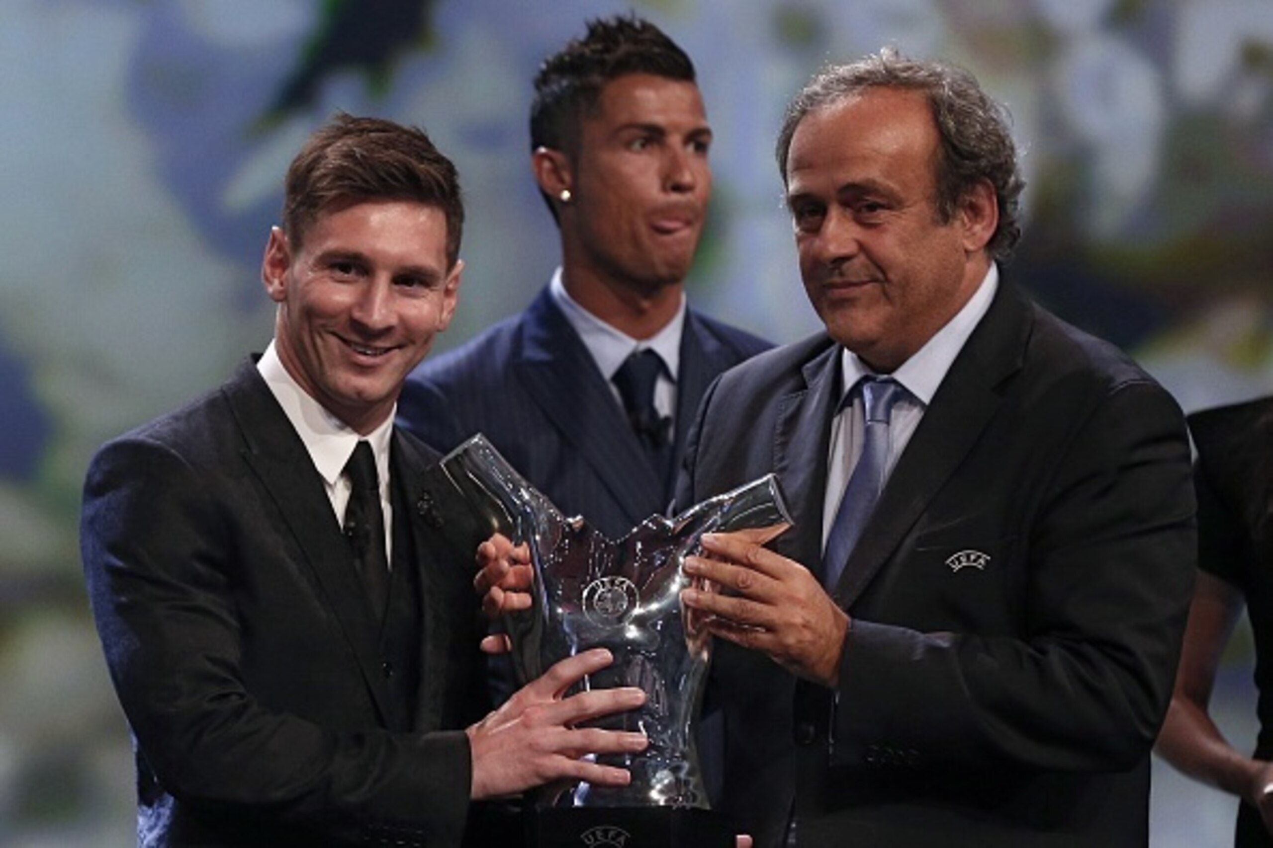 FC Barcelone Argentinian striker Lionel Messi receives from UEFA president Michel Platini (R) the trophy of Best Men's player in Europe next to runner-up Portugal's Cristiano Ronaldo at the end of the UEFA Champions League Group stage draw ceremony, on Au