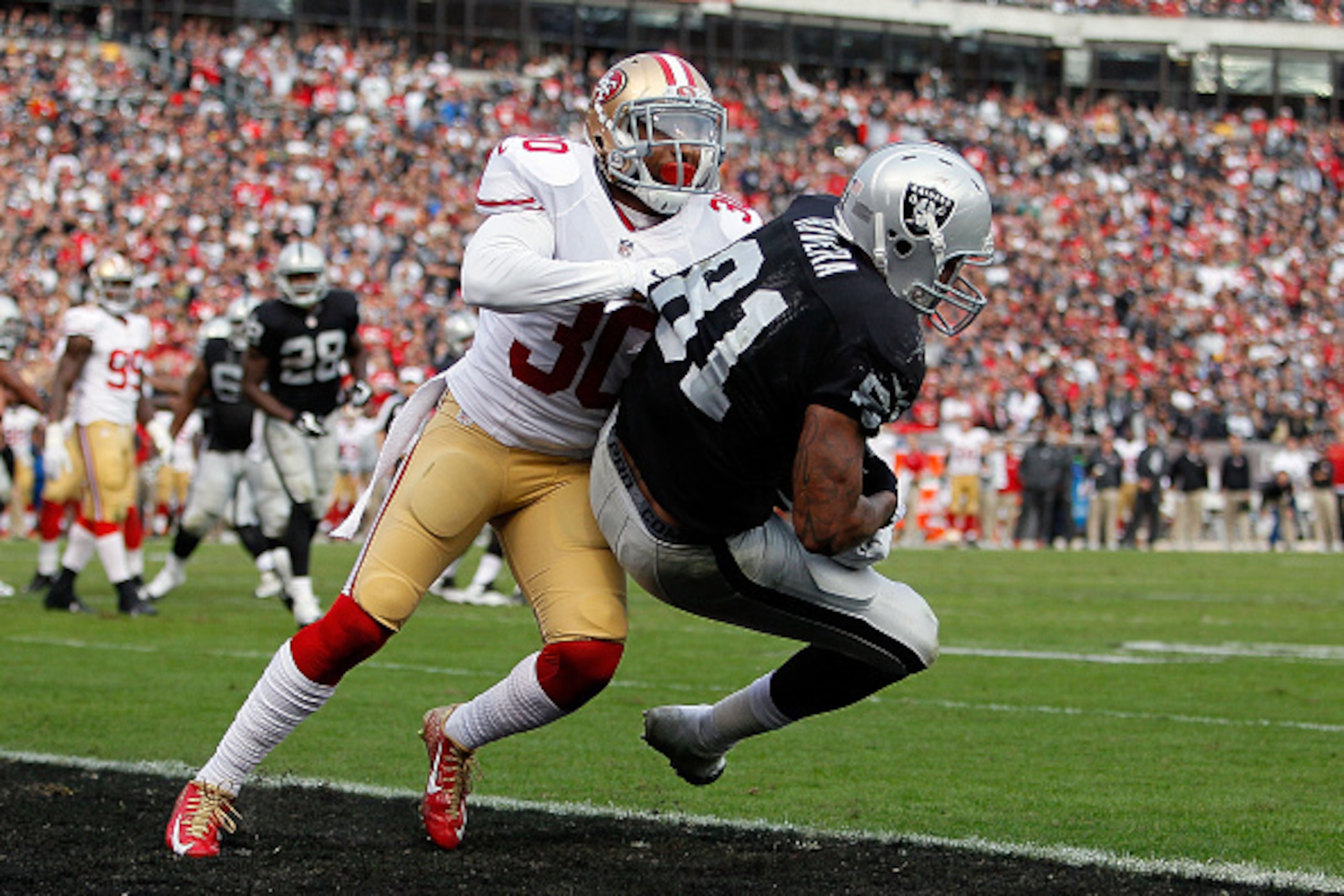 OAKLAND, CA - DECEMBER 07:  Mychal Rivera #81 of the Oakland Raiders scores a touchdown in the fourth quarter in front of Leon McFadden #30 of the San Francisco 49ers  at O.co Coliseum on December 7, 2014 in Oakland, California.  (Photo by Brian Bahr/Gett