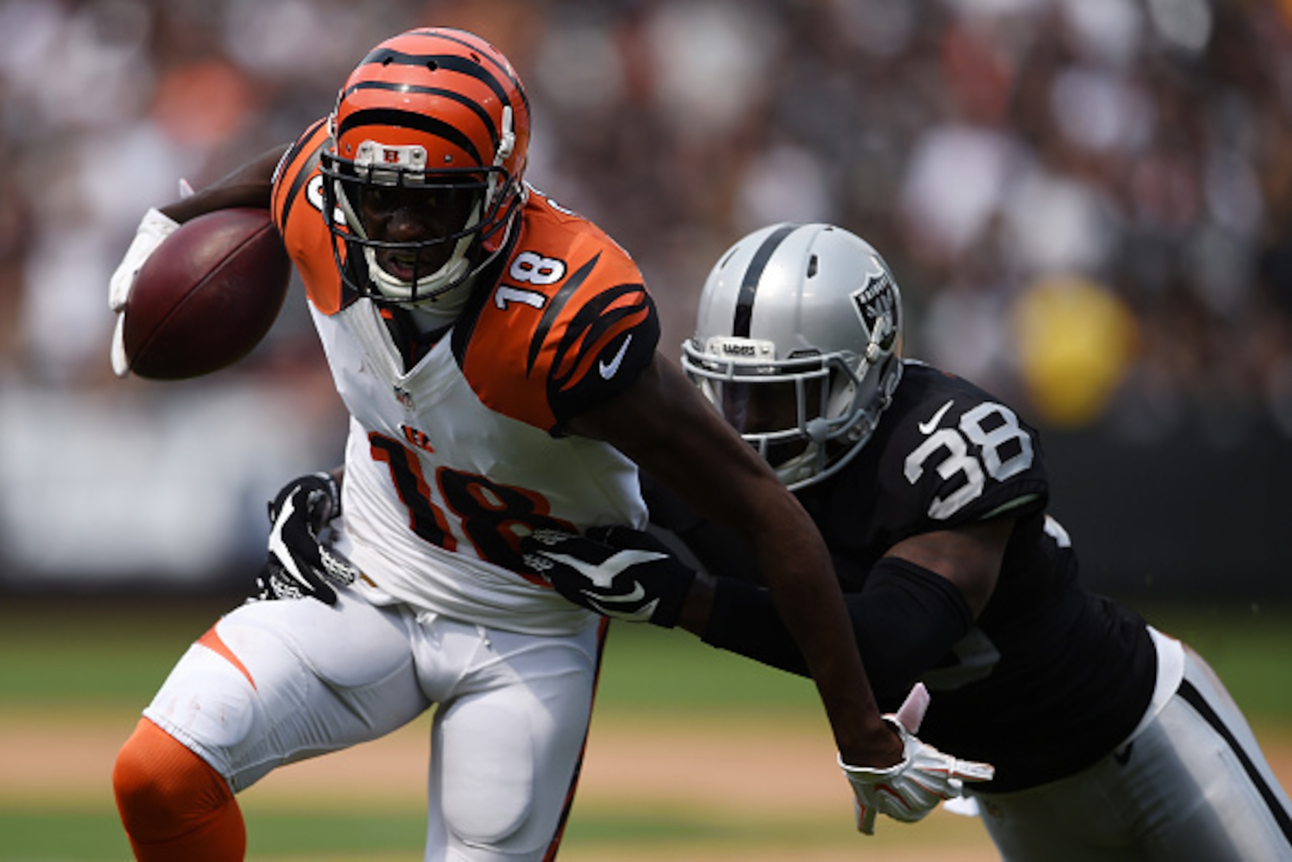 OAKLAND, CA - SEPTEMBER 13:  A.J. Green #18 of the Cincinnati Bengals is tackled by TJ Carrie #38 of the Oakland Raiders during the first half of their NFL game at O.co Coliseum on September 13, 2015 in Oakland, California.  (Photo by Thearon W. Henderson