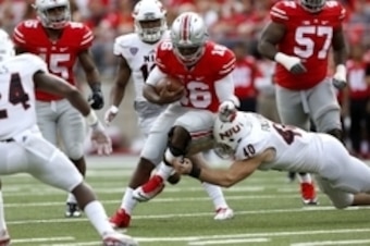 Sep 19, 2015; Columbus, OH, USA; Ohio State Buckeyes quarterback J.T. Barrett (16) gets free for a gain as Northern Illinois Huskies linebacker Sean Folliard (40) tackles during the second quarter at Ohio Stadium. The game is tied 10-10 at half.  Mandator