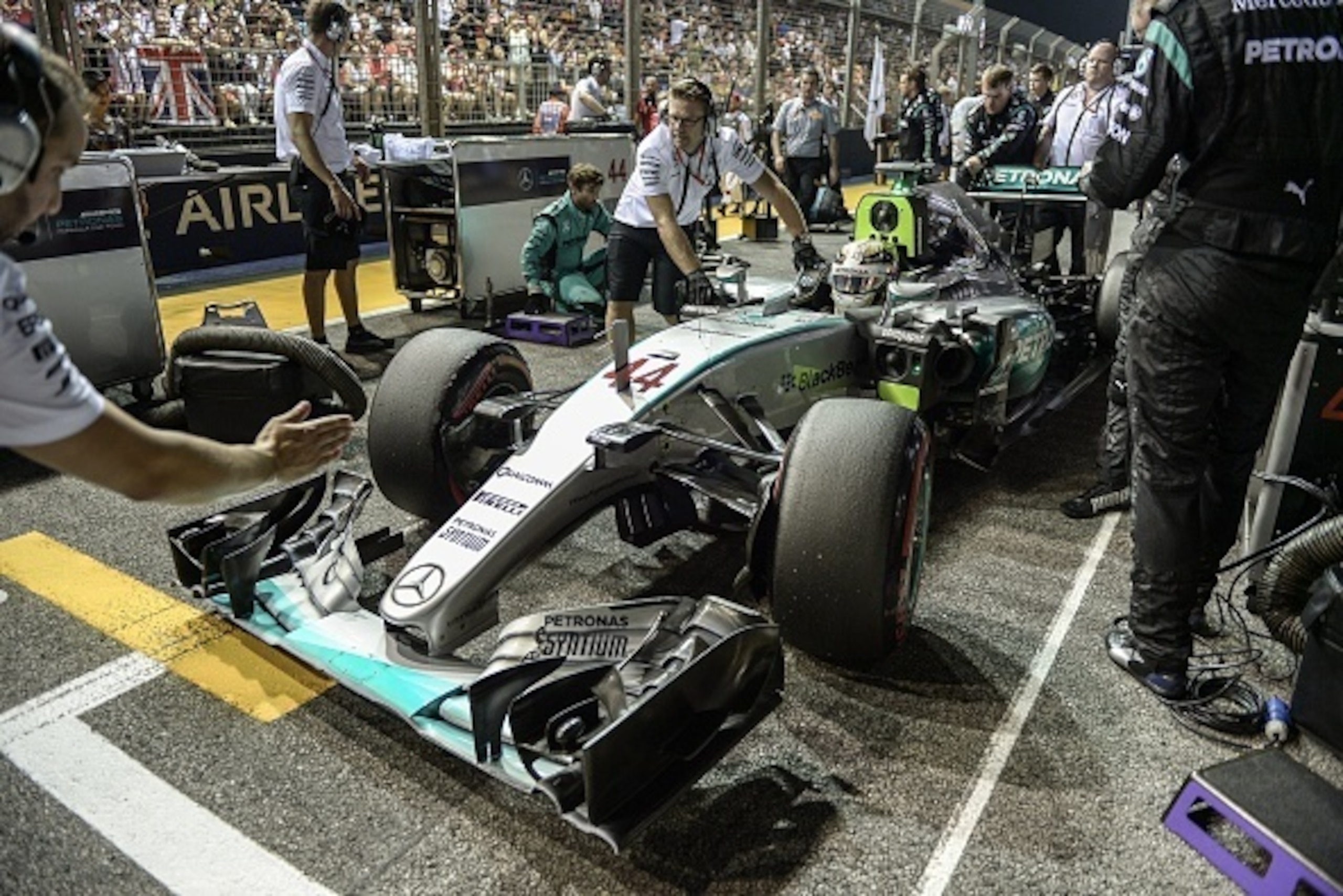 Mechanics attend to the car of Mercedes AMG Petronas F1 Team's British driver Lewis Hamilton prior to the start of the Formula One Singapore Grand Prix in Singapore on September 20, 2015. AFP PHOTO / MOHD RASFAN        (Photo credit should read MOHD RASFA