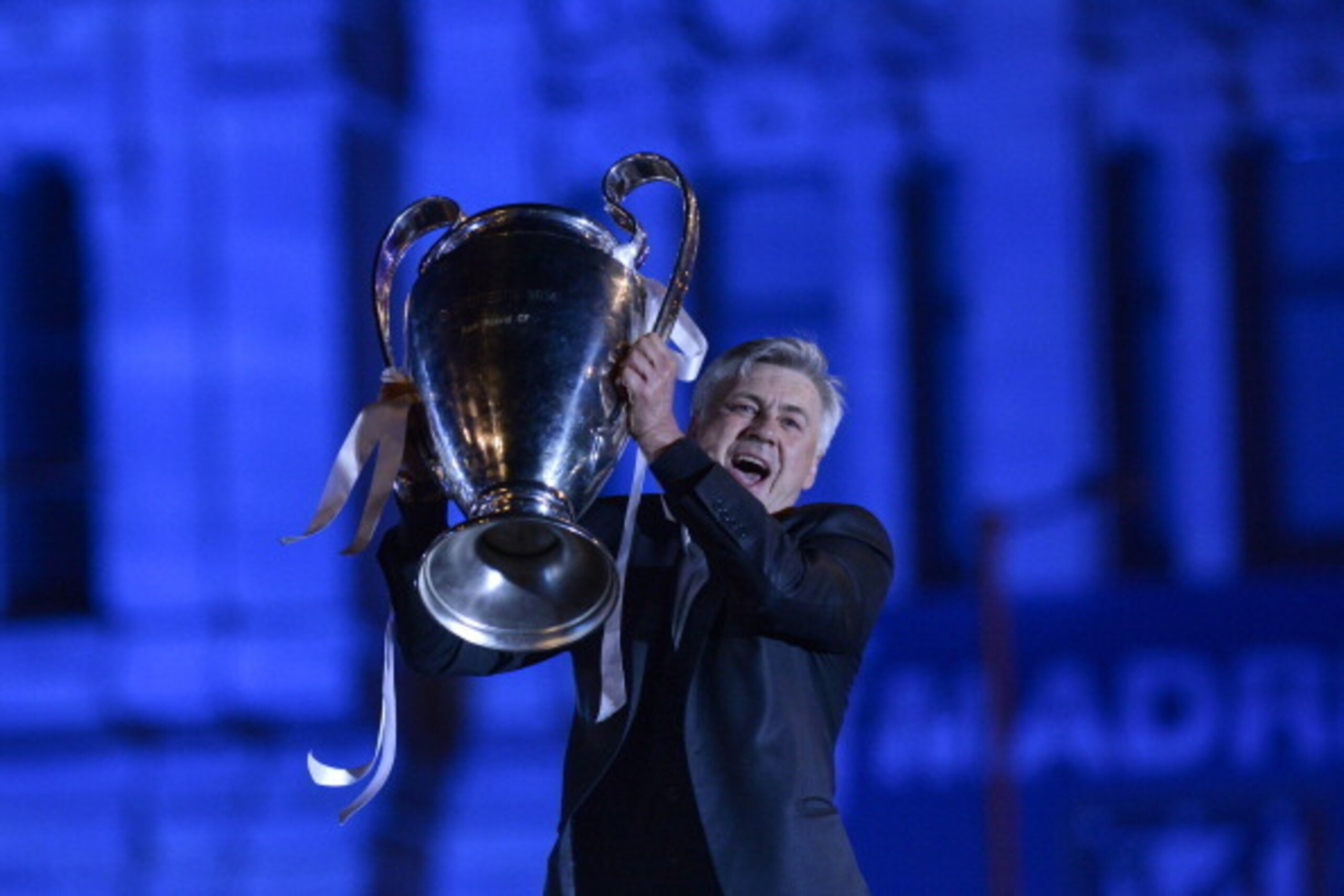 Real Madrid's Italian coach Carlo Ancelotti holds the trophy as the team celebrates their UEFA Champions League final win with fans at Cibeles Square in Madrid on May 24, 2014 after the football match against Atletico Madrid held at the Luz stadium in Lis