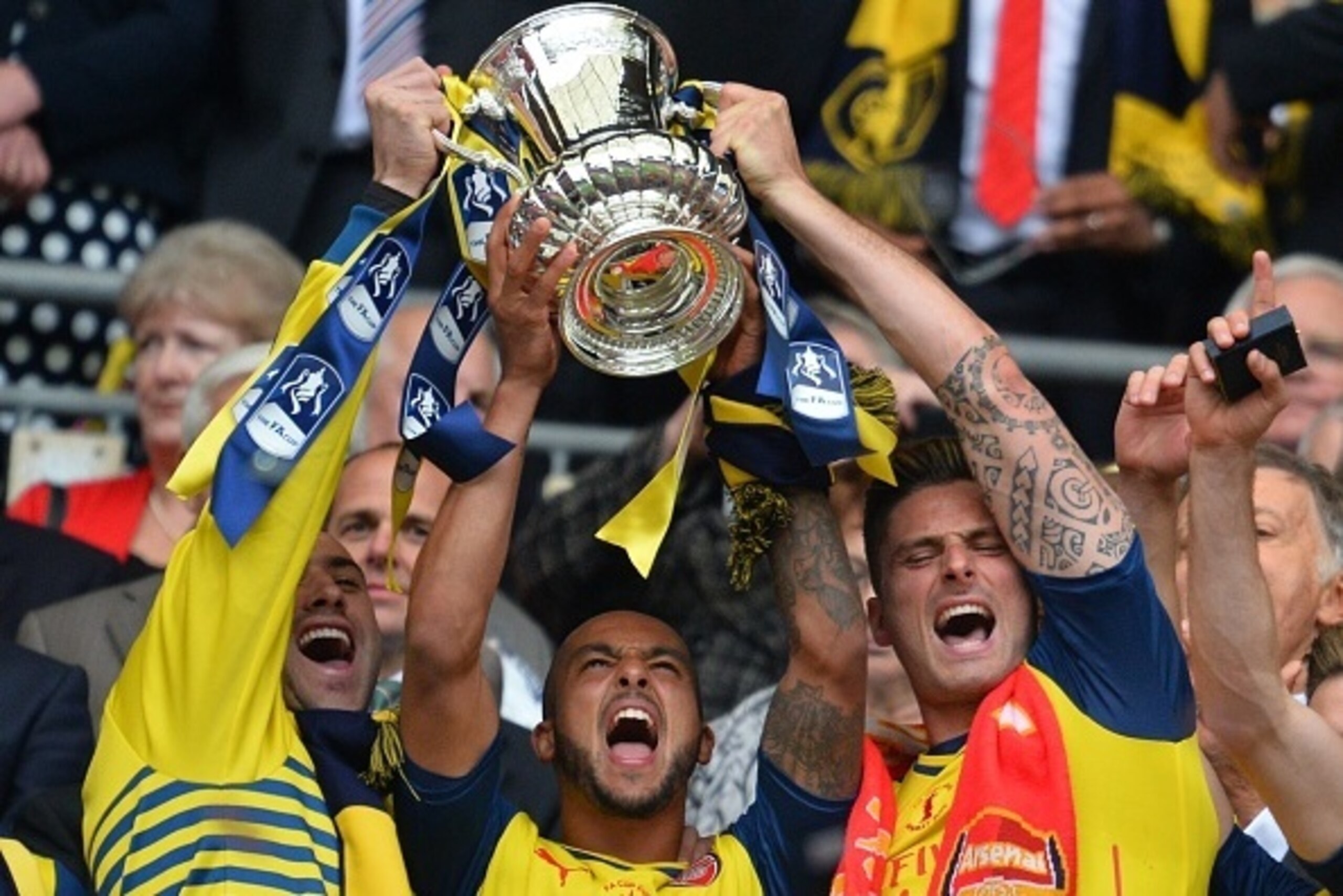 Arsenal's English midfielder Theo Walcott (C) and Arsenal's French striker Olivier Giroud (R) hold up the trophy after winning the FA Cup final football match between Aston Villa and Arsenal at Wembley stadium in London on May 30, 2015.       AFP PHOTO / 