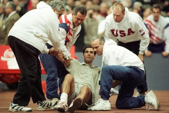 1 DEC 1995:  PETE SAMPRAS OF THE USA IS HELPED TO HIS FEET BY USA TEAM OFFICIALS AFTER COLLAPSING ON MATCH POINT DURING HIS OPENING MATCH AGAINST RUSSIA S ANDREI CHESNOKOV AT THE USA V RUSSIA DAVIS CUP FINAL IN MOSCOW, RUSSIA.  SAMPRAS WON THE MATCH IN 5S