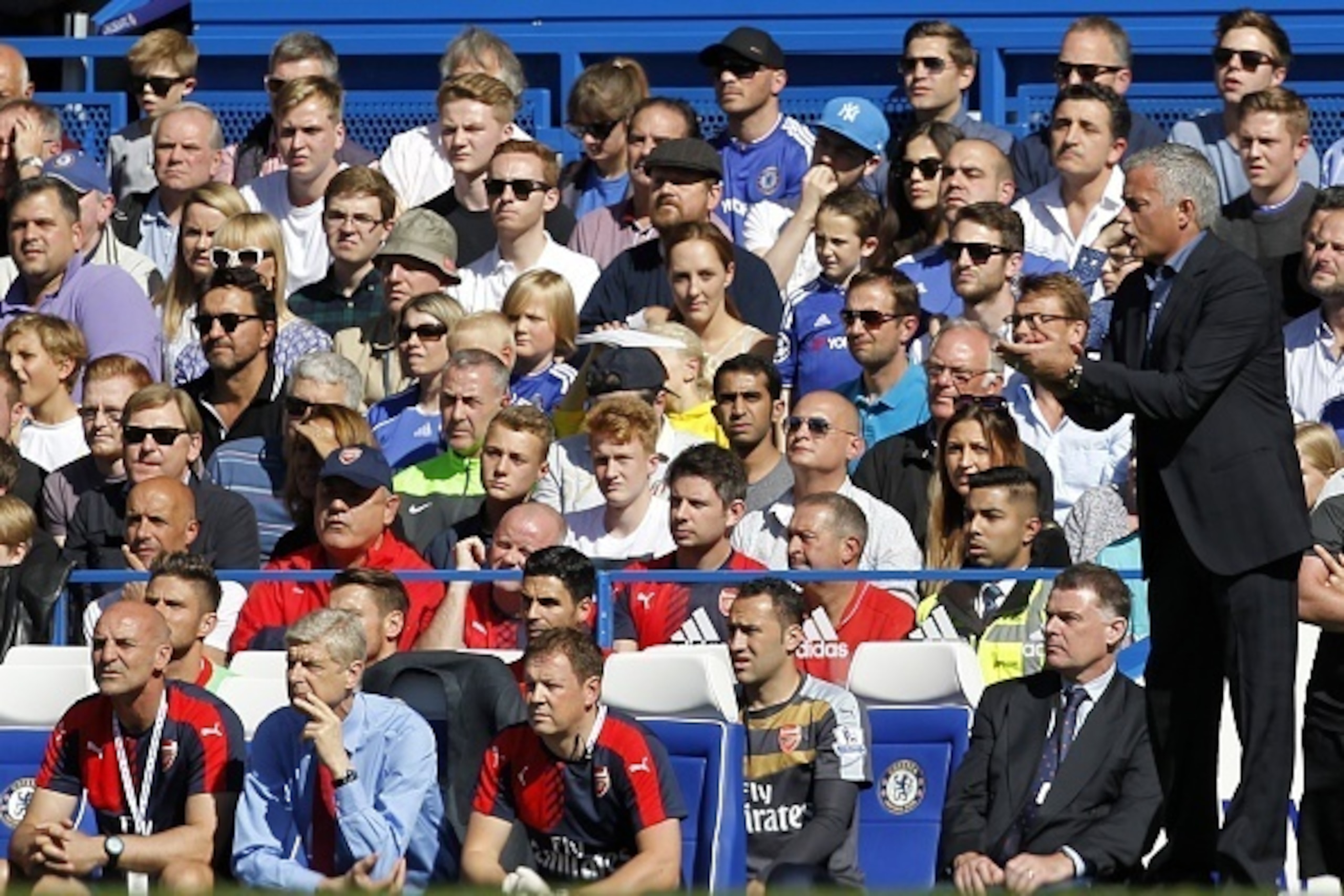 Chelsea's Portuguese manager Jose Mourinho (R) gestures as Arsenal's French manager Arsene Wenger (front row 2nd L) sits watching the English Premier League football match between Chelsea and Arsenal at Stamford Bridge in London on September 19, 2015. AFP