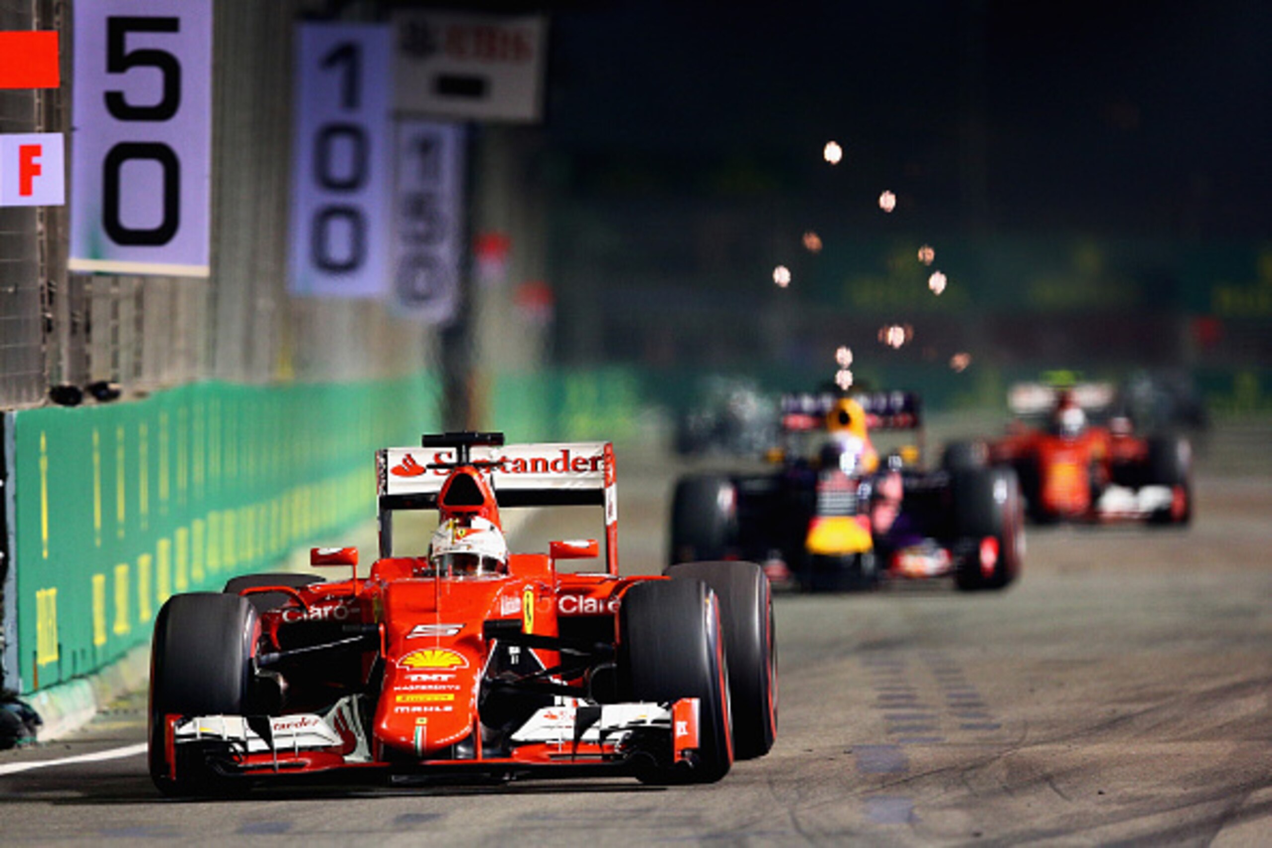 SINGAPORE - SEPTEMBER 20:  Sebastian Vettel of Germany and Ferrari drives ahead of Daniel Ricciardo of Australia and Infiniti Red Bull Racing and Kimi Raikkonen of Finland and Ferrari during the Formula One Grand Prix of Singapore at Marina Bay Street Cir