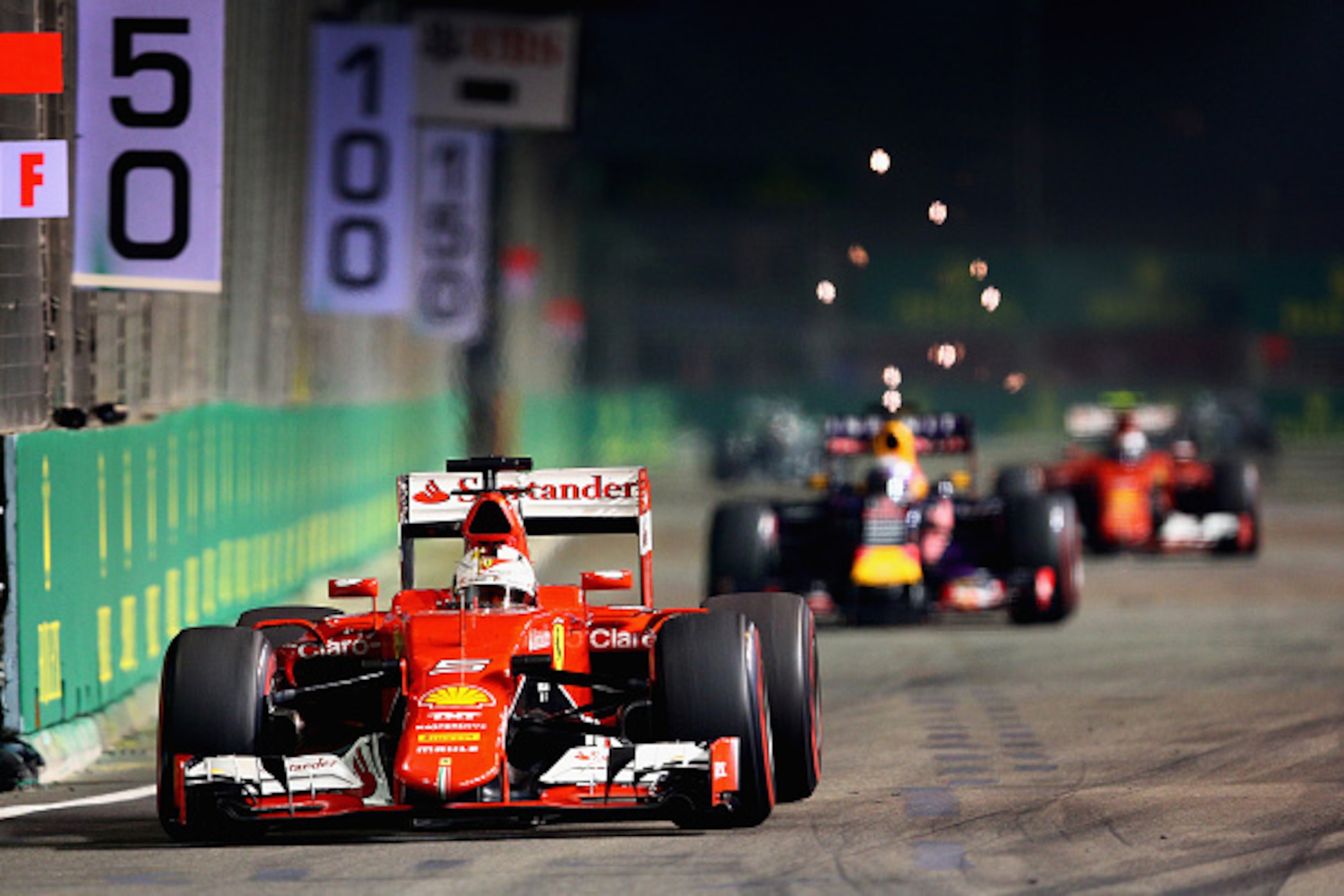 SINGAPORE - SEPTEMBER 20:  Sebastian Vettel of Germany and Ferrari drives ahead of Daniel Ricciardo of Australia and Infiniti Red Bull Racing and Kimi Raikkonen of Finland and Ferrari during the Formula One Grand Prix of Singapore at Marina Bay Street Cir