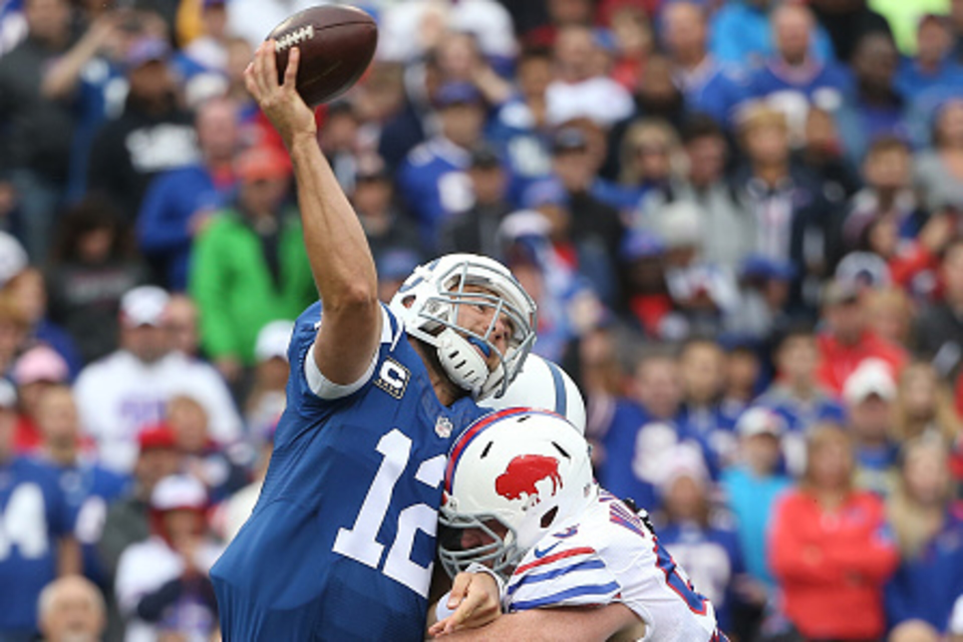 ORCHARD PARK, NY - SEPTEMBER 13: Andrew Luck #12 of the Indianapolis Colts is hit as he throws during NFL game action by Kyle Williams #95 of the Buffalo Bills at Ralph Wilson Stadium on September 13, 2015 in Orchard Park, New York. (Photo by Tom Szczerbo