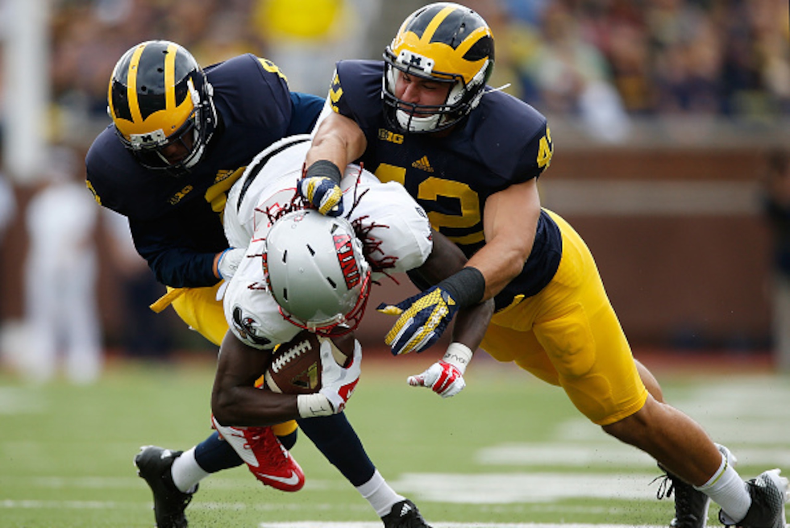 ANN ARBOR, MI - SEPTEMBER 19:  Channing Stribling #8 of the Michigan Wolverines and teammate Ben Gedeon #42 tackle Devonte Boyd #83 of the UNLV Rebels on September 19, 2015 at Michigan Stadium in Ann Arbor, Michigan.  (Photo by Gregory Shamus/Getty Images