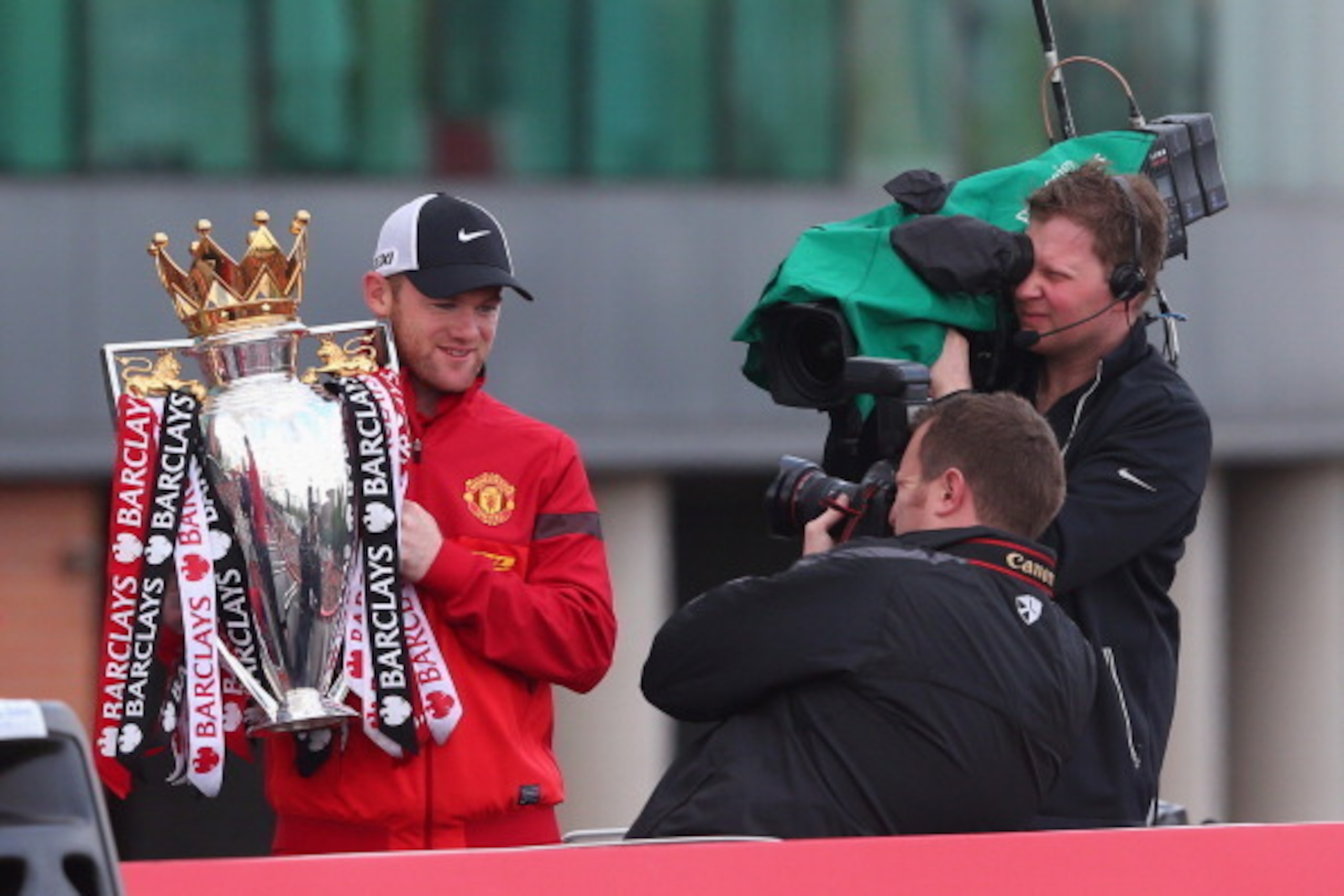 MANCHESTER, ENGLAND - MAY 13:  Wayne Rooney holds the Barclays Premier League Trophy aloft on the open topped bus outside Old Trafford during the Manchester United Premier League winners parade on May 13, 2013 in Manchester, England.  (Photo by Alex Lives